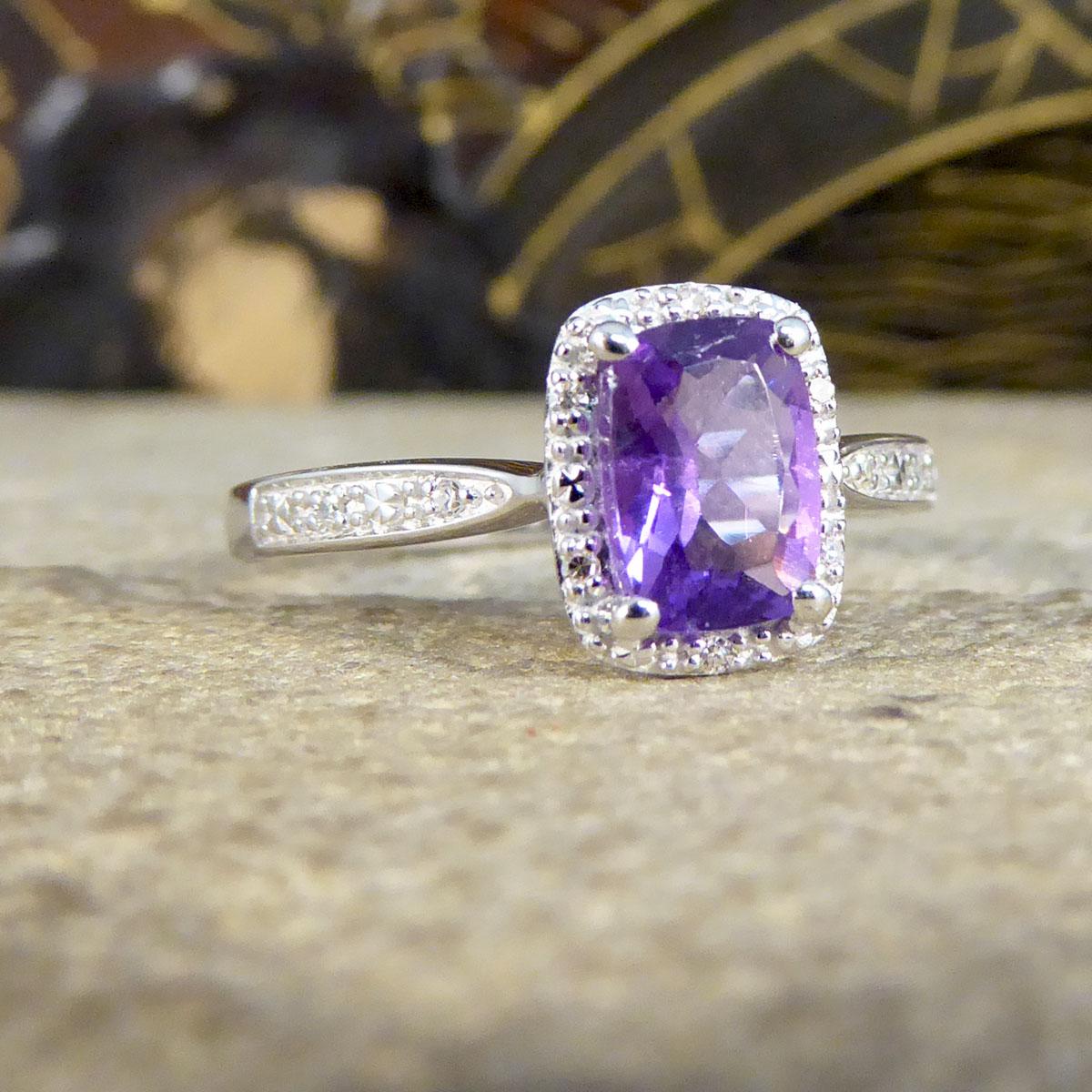 Dieser zeitgenössische Ring zeigt einen einzelnen Amethyst-Edelstein mit einer leuchtend violetten Färbung in einer Fassung mit vier Krallen. Der wunderschöne Amethyst ist von einem Illusionshalo mit 6 kleinen Diamanten umgeben, einer oben und unten