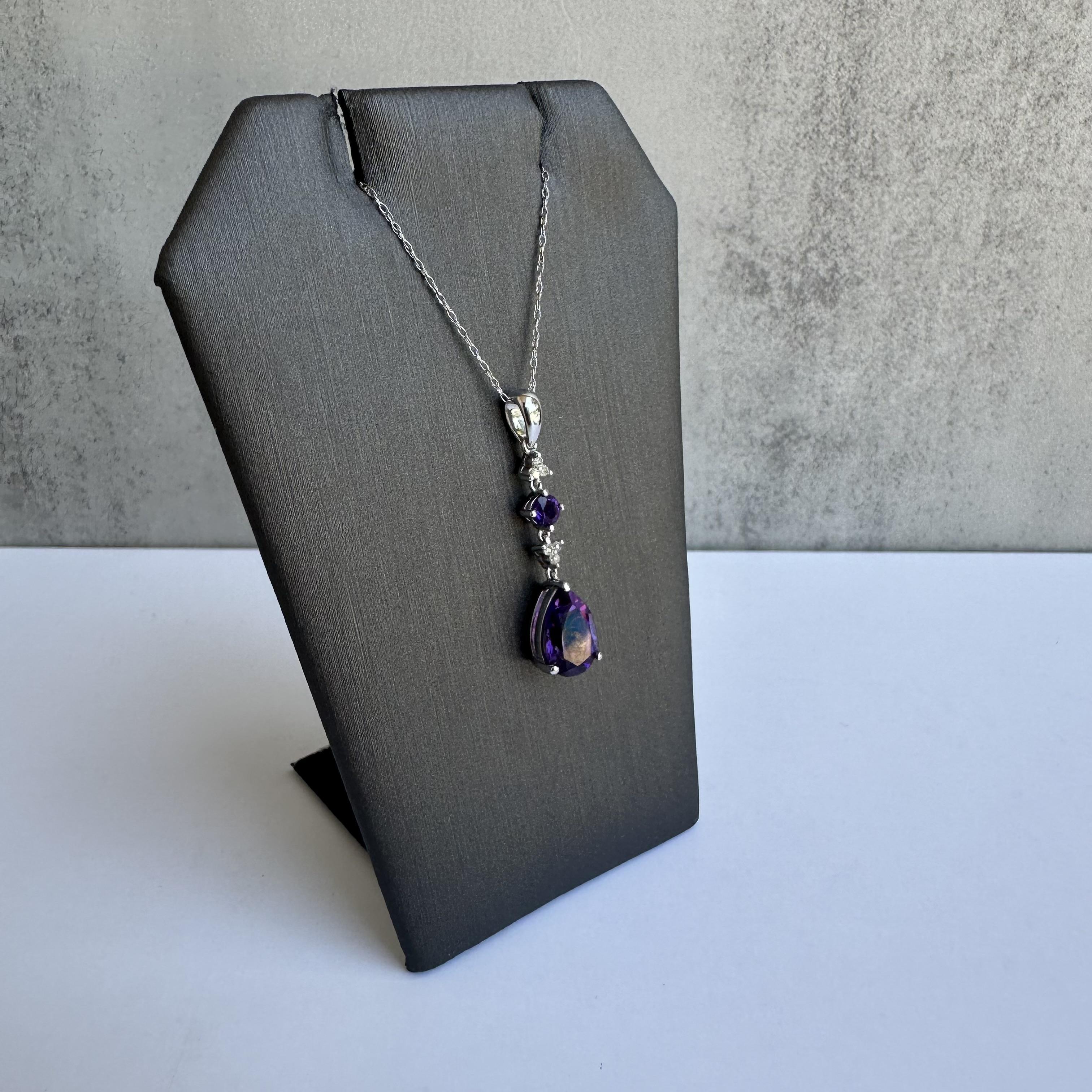 Enhance your jewelry collection with this exquisite Amethyst and Diamond Necklace in 10kt White Gold. Featuring a 10x7mm pear amethyst, a 3.4mm round amethyst, and 0.05 carats of IJ SI natural round single cut diamonds, this necklace combines