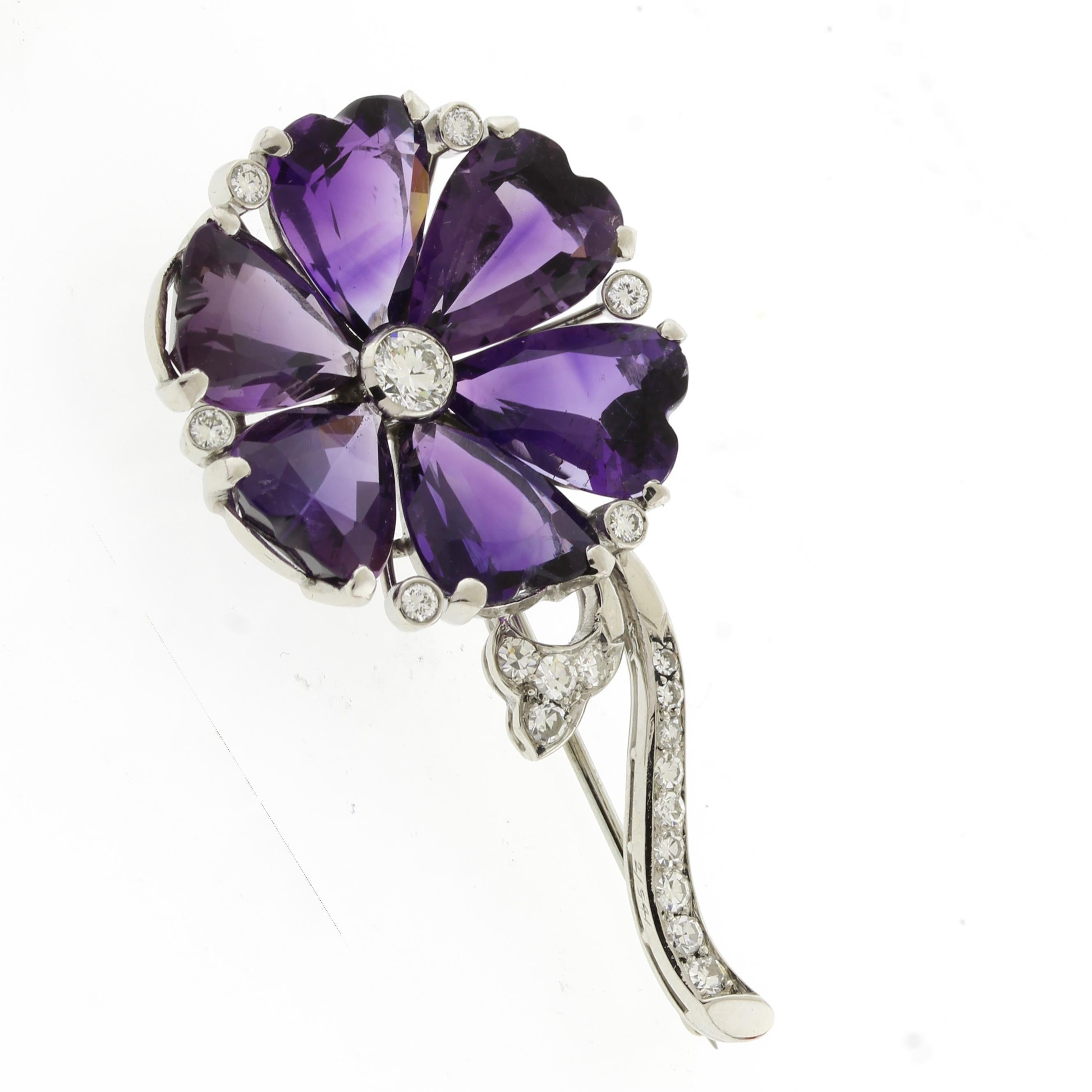 From the Mid-Century, a flower brooch with 6 Amethyst heart shaped flower petals and a diamond stem.
• Metal: Platinum	
• Circa: Mid-Century
•Gemstone: 6 Amethysts stones
20Diamonds, 19D=.45carats and 1 center diamond=.35 carats
• Weight: 12.3