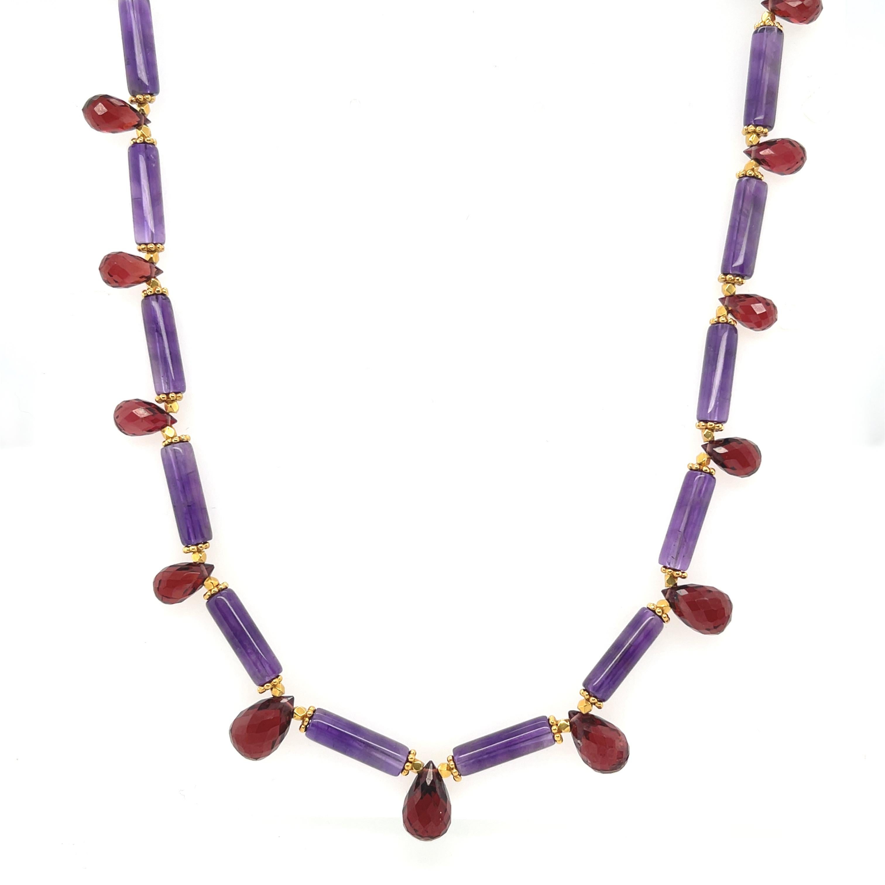 Ce collier de pierres précieuses colorées présente une belle collection de perles tubulaires d'améthyste de forme inhabituelle, arrangées avec de riches briolettes de grenat rouge et des accents d'or jaune 18k. L'améthyste est d'une couleur pourpre