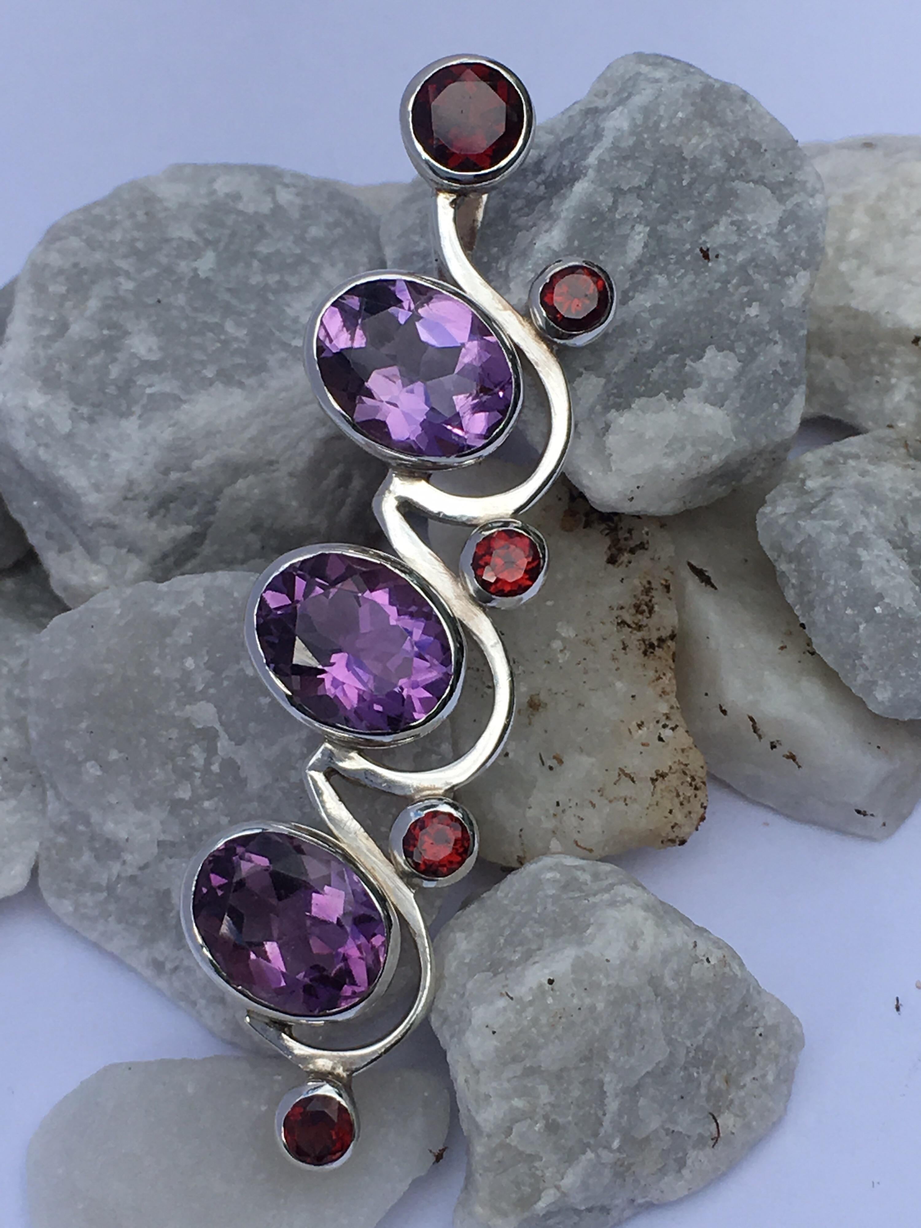 Oval Amethyst 7 MM X 9 MM , Round Garnet 5 MM and other  round Garnet 3 MM set in sterling silver.
All the stones are hand cut and polished .
The pendant is hand crafted by skilled silver smith.
Silver chain is included with the purchase. 