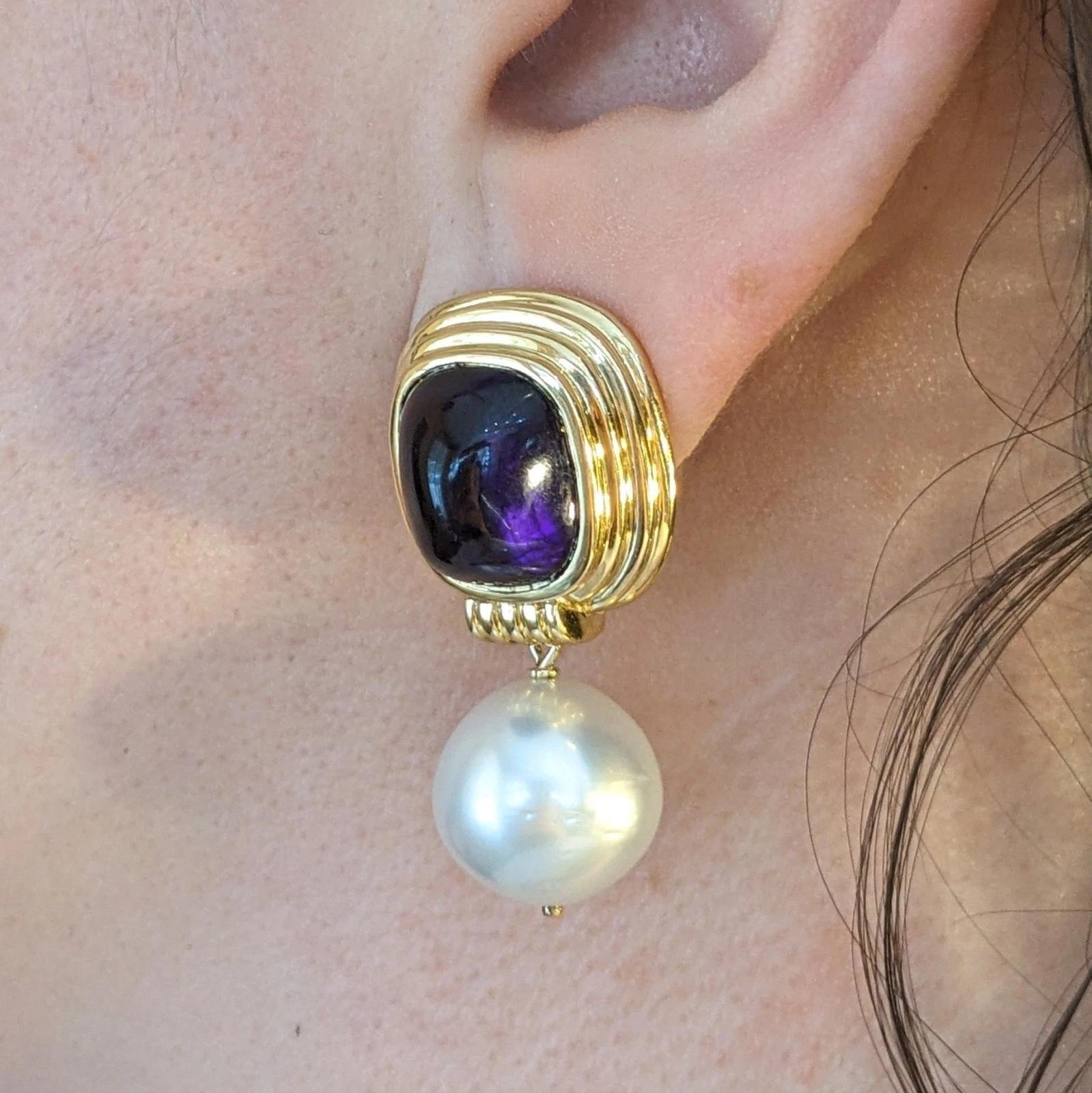 Orecchini pendenti con ametista e perla in oro giallo 18 carati 

Gli orecchini con ametista e perle sono caratterizzati da ametiste cabochon a cupola alta incastonate in un castone a strati con perle bianche dei mari del sud da 14 mm, il tutto