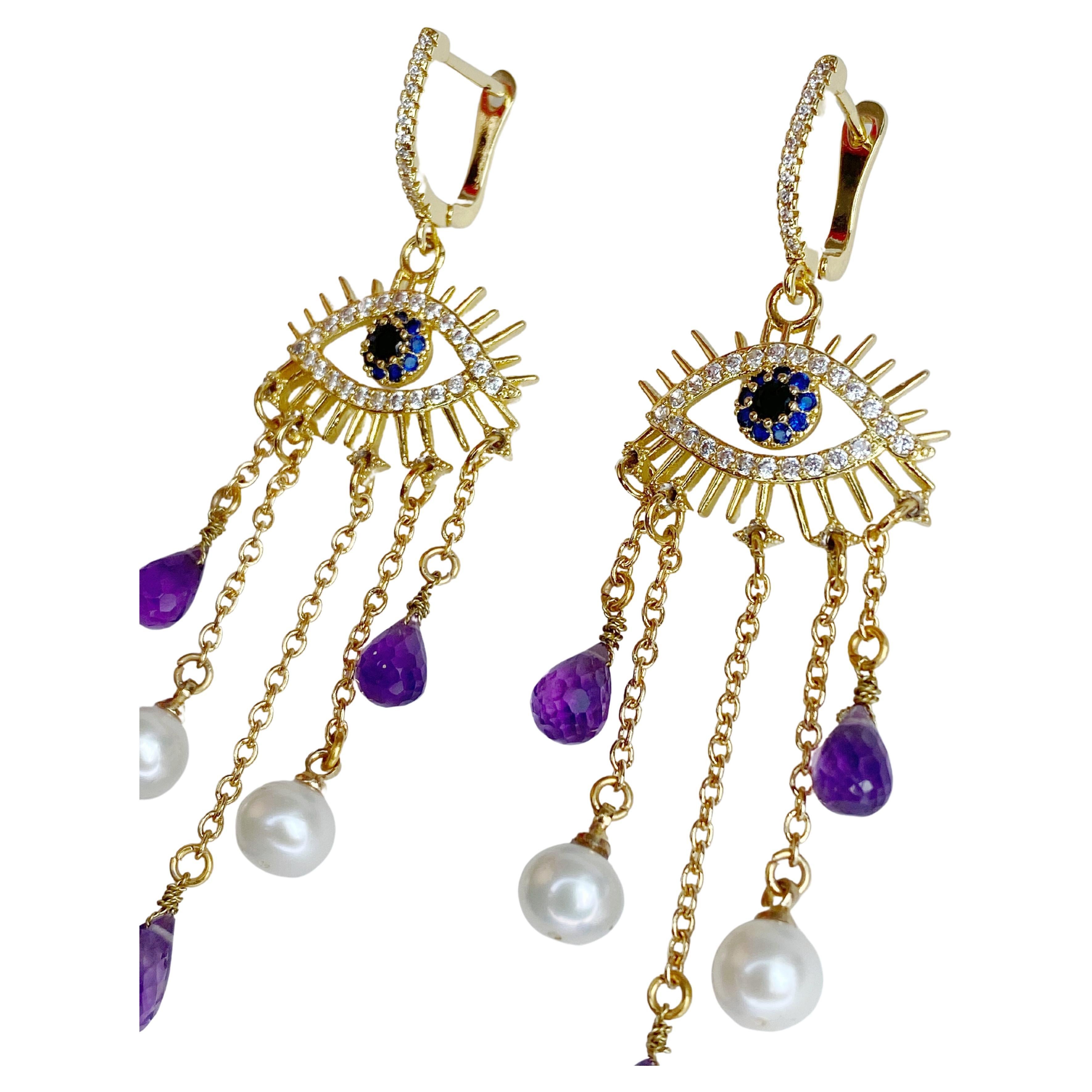 This whimsical pair of gold plated earrings feature Swarovski crystals and drop strands set with natural faceted Amethyst and freshwater pearls.  Lightweight yet eye catching design make these earrings a fun and elegant alternative.