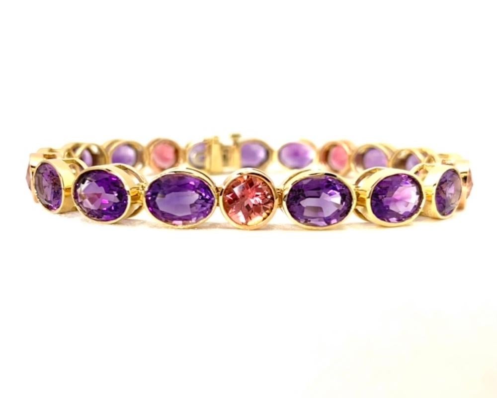 Bright amethyst ovals and sparkling round pink tourmalines are featured in this beautiful 18k yellow and rose gold tennis bracelet! 26 carats of lively purple amethysts are bezel set in 18k yellow gold, while the sparkling peachy pink tourmalines