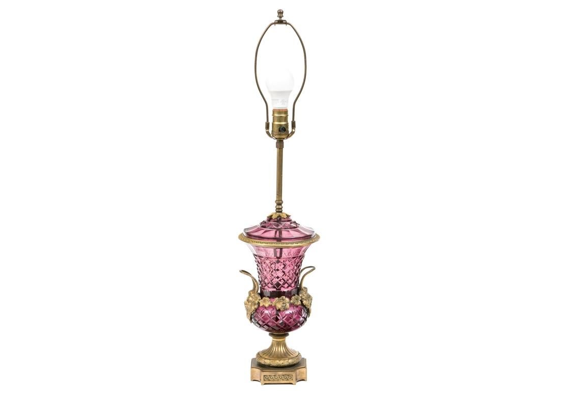 A spectacular amethyst vase featuring faceted diamond cuts, fan cuts and faceted border. The lamp with bronze Bacchus masks with handles, hand-chased grape leaves and an egg/dart rim, resting on a pedestal base with laurel leaves and berries and