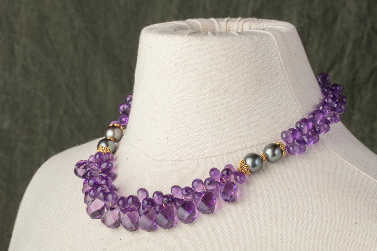 A combination of amethyst briolettes in both a large and smaller sizes clustered together at the center with 22K gold and Tahitian pearls at the collar bone with smaller briolette gemstones along the back.   Cluster at the center between the pearls
