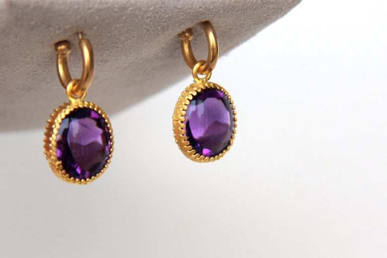 Fancy Amethyst buff top drops on gold hoops, 22 karat gold scalloped settings. 
Amethysts were revered by the Ancient Greeks and Romans as a stone symbolizing luxury and were often highlighted as a part of their crowns, scepters, and rings.
Hand