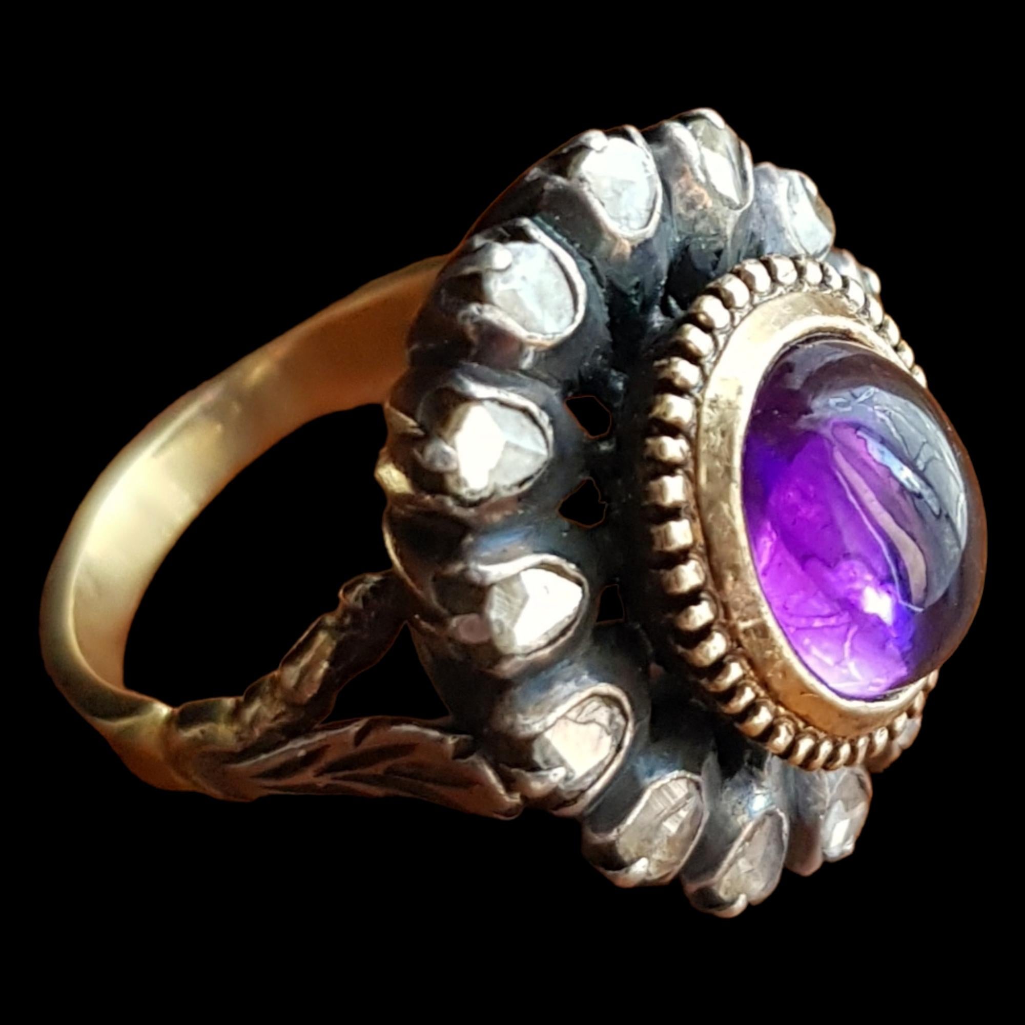 AMETHYST CABOCHON AND ROSE CUT DIAMOND RING

A lovely early Victorian ring set with a good deep color, bright purple cabochon shaped amethyst measuring approx. 2.70 carats (9.22X7.74X5.24mm). Surrounding it are graded 14 rose cut diamonds. The top