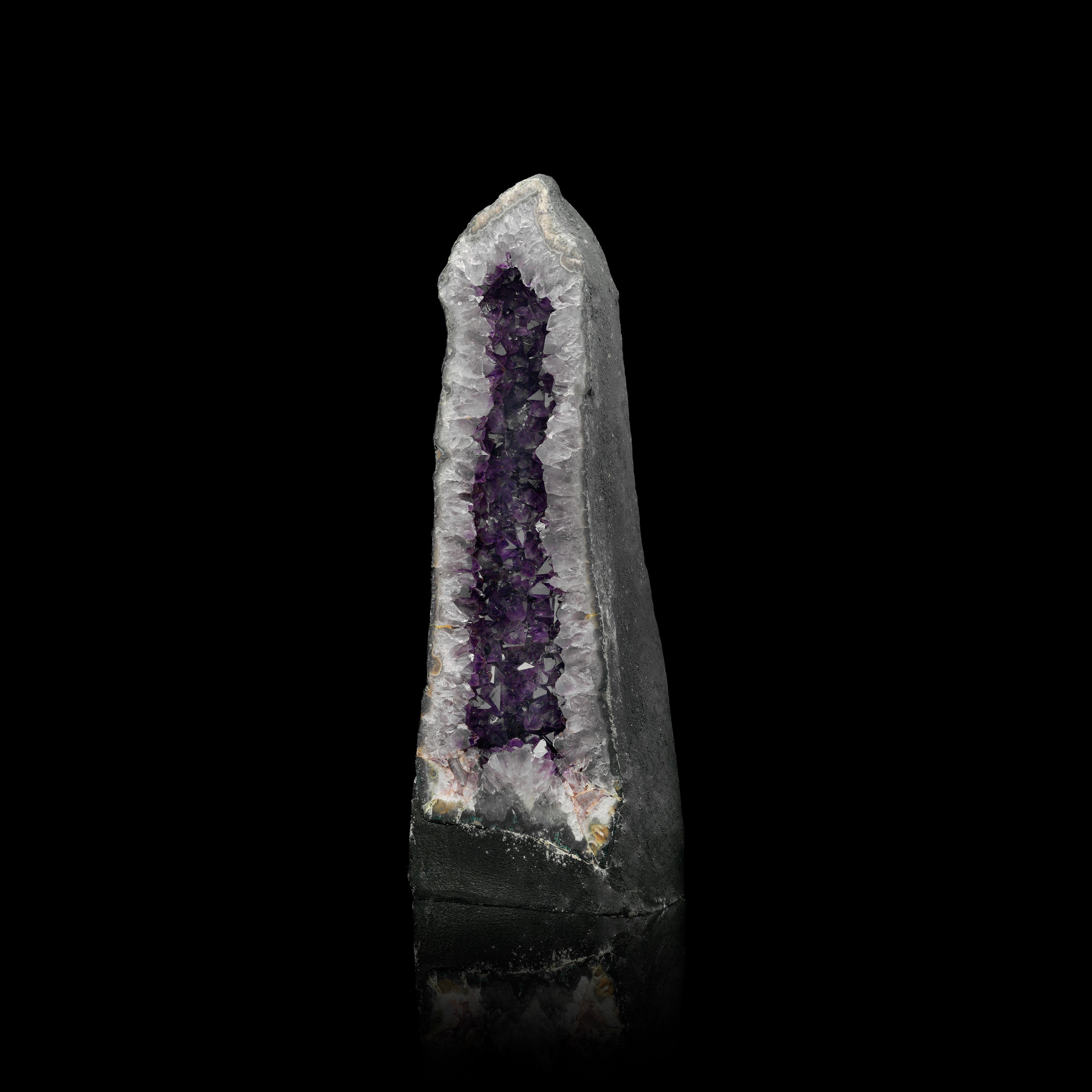 This tall and elegant Amethyst Cathedral from Brazil showcases a dazzling column of deep purple crystals, framed by a beautifully polished edge. Its graceful height and rich coloration make it a stunning centerpiece for any gallery, home, or
