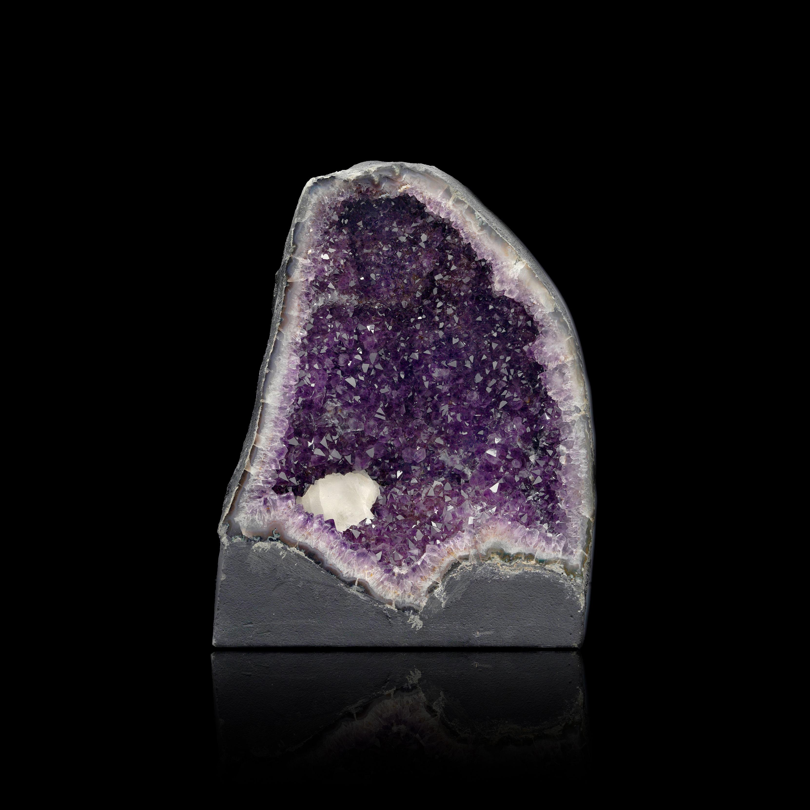 Questa straordinaria cattedrale di ametista proveniente dal Brasile presenta una straordinaria inclusione di quarzo che aggiunge uno strato di bellezza naturale e di intrigo alle sue vibranti formazioni di cristallo viola. I bordi lucidi evidenziano