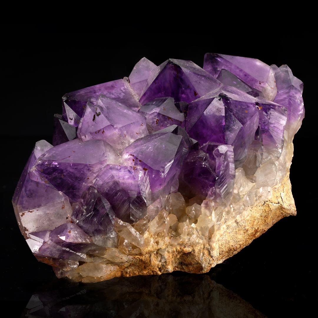 This large and lustrous, deeply pigmented, grape jelly purple AAA grade amethyst cluster features large, beautifully fully terminated and fully formed crystals on matrix out of Central Africa. A gemmy display piece sure to elevate the ambience of