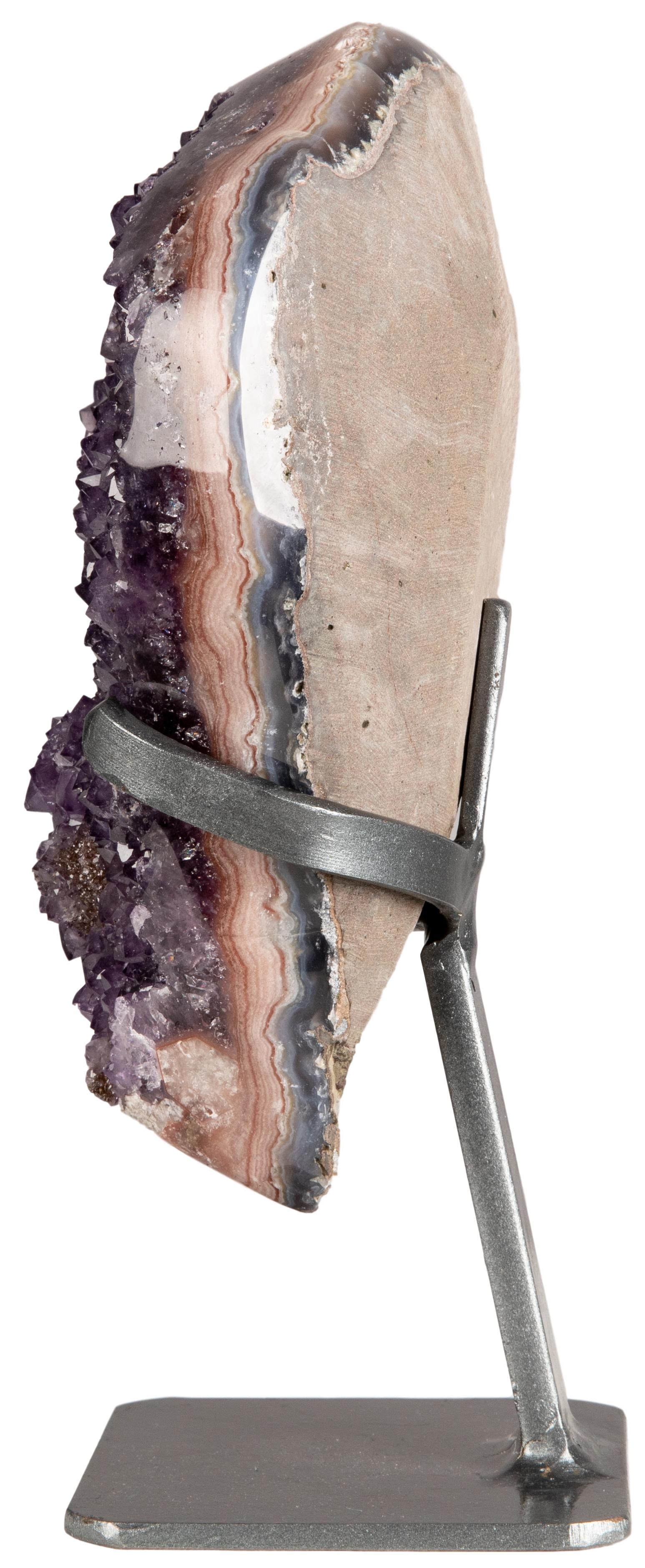An exquisite deep purple amethyst cluster with mineral formation and a polished stalactite. This natural piece is surrounded and adorned with a beautiful polished border, where it is possible to see the mineral layers developing from the rough