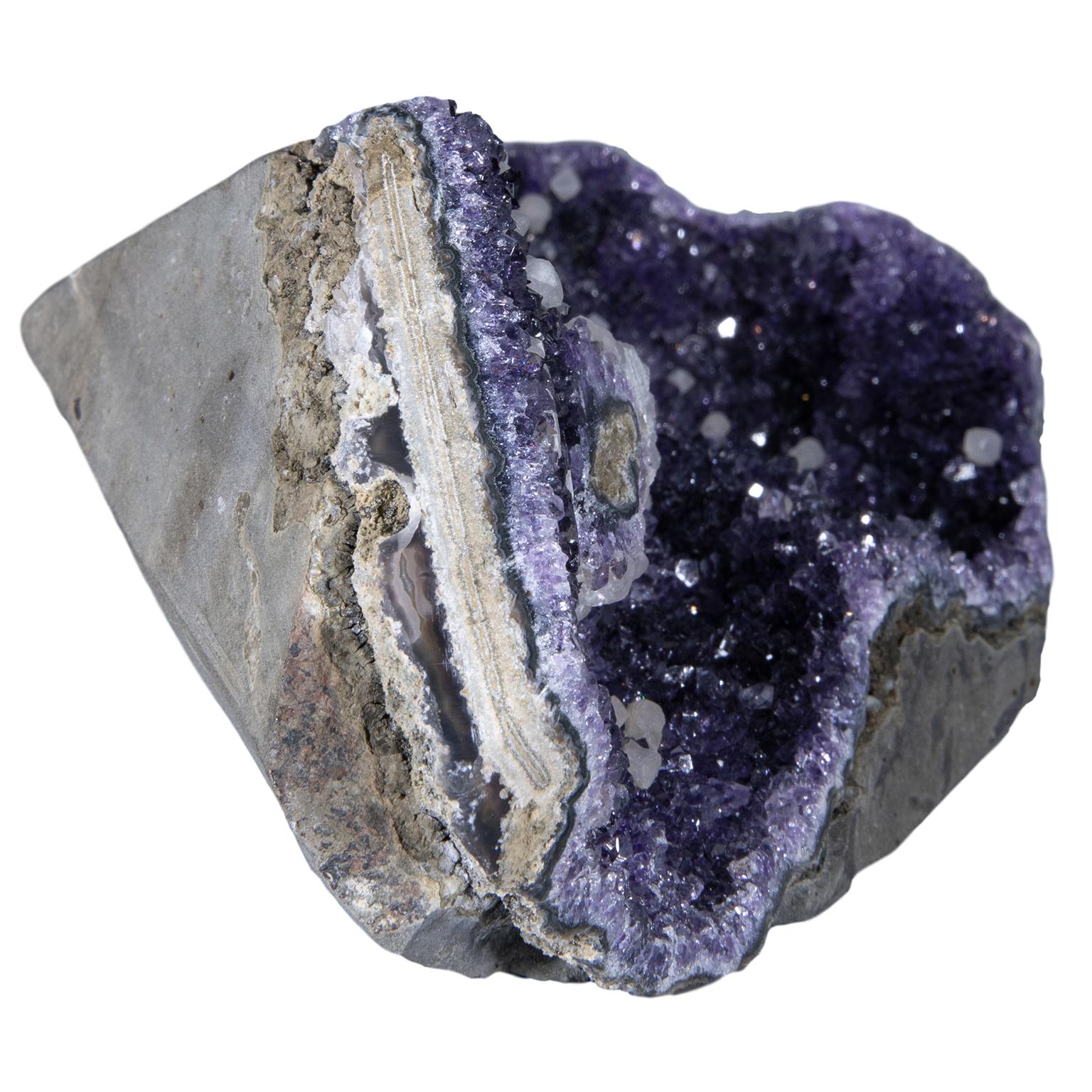 A stunning rough amethyst cluster with calcite crystals.

This piece has an exquisite purple color and a calcite formation on the top. To further add to its beauty, this piece has calcite crystal 