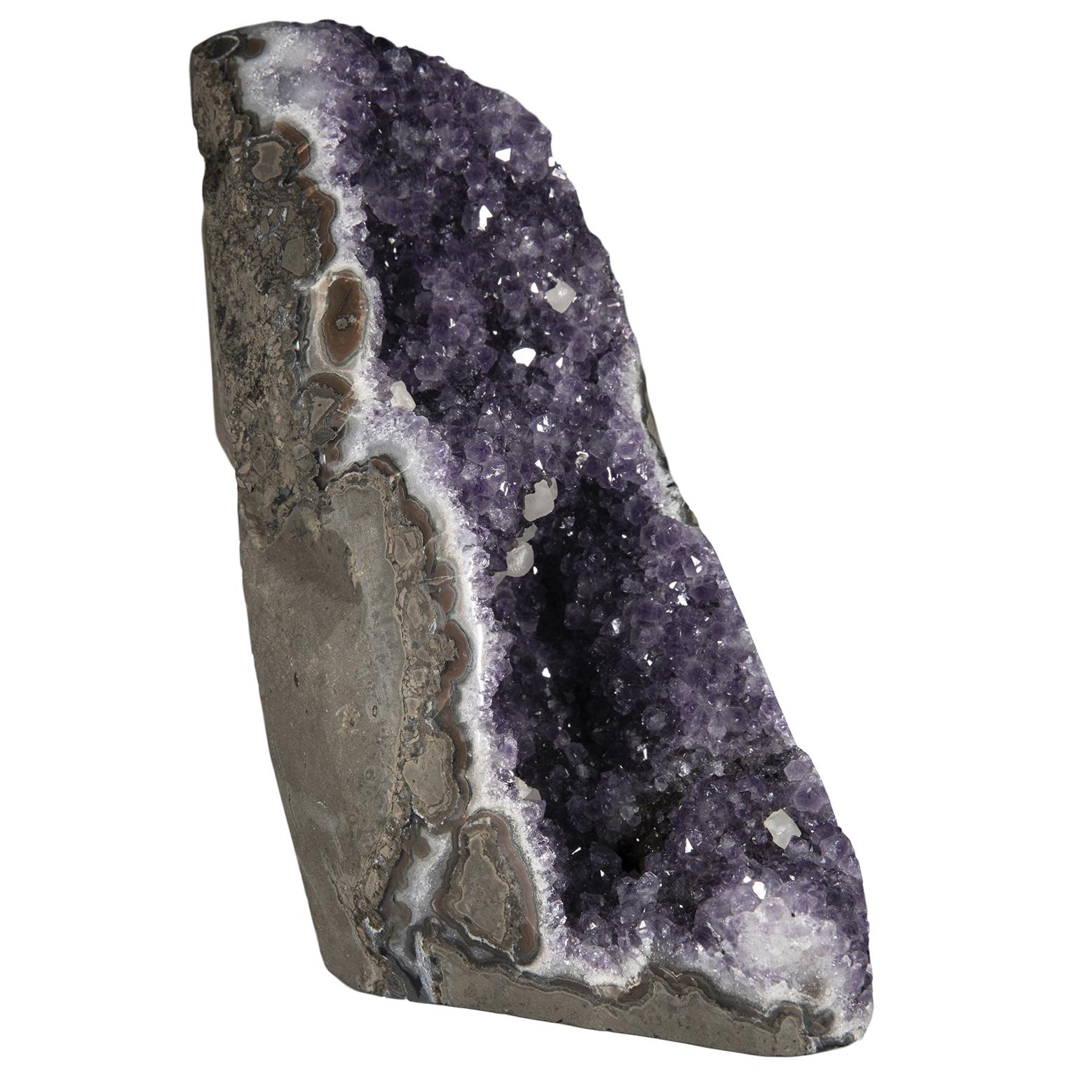 An exquisite and rare amethyst cluster with stalactite formations and calcite crystals.

The stunning piece’s shape resembles a “Cascade” or “waterfall”, giving intensity to the crystal color.

To further add to its beauty, this piece has