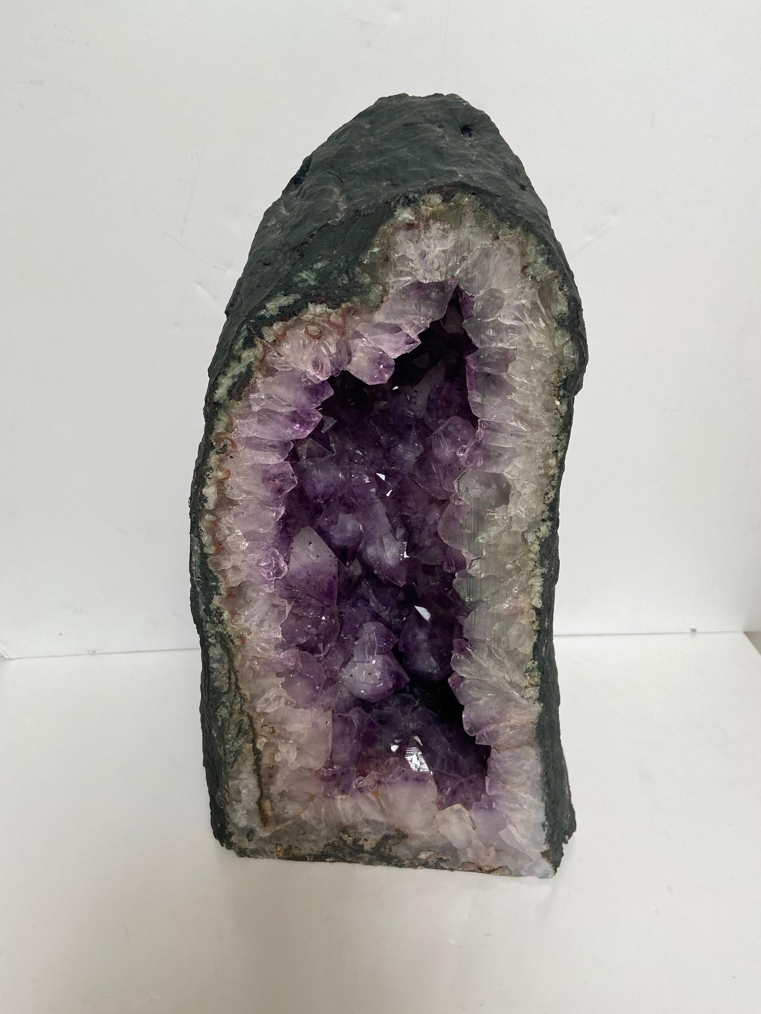 Amethystkristall Höhle eine auffallende geschliffene und polierte Amethystquarzgeode hohe bergige Form, der einzelne polierte Schliff zeigt tief violetten Amethystkristall.