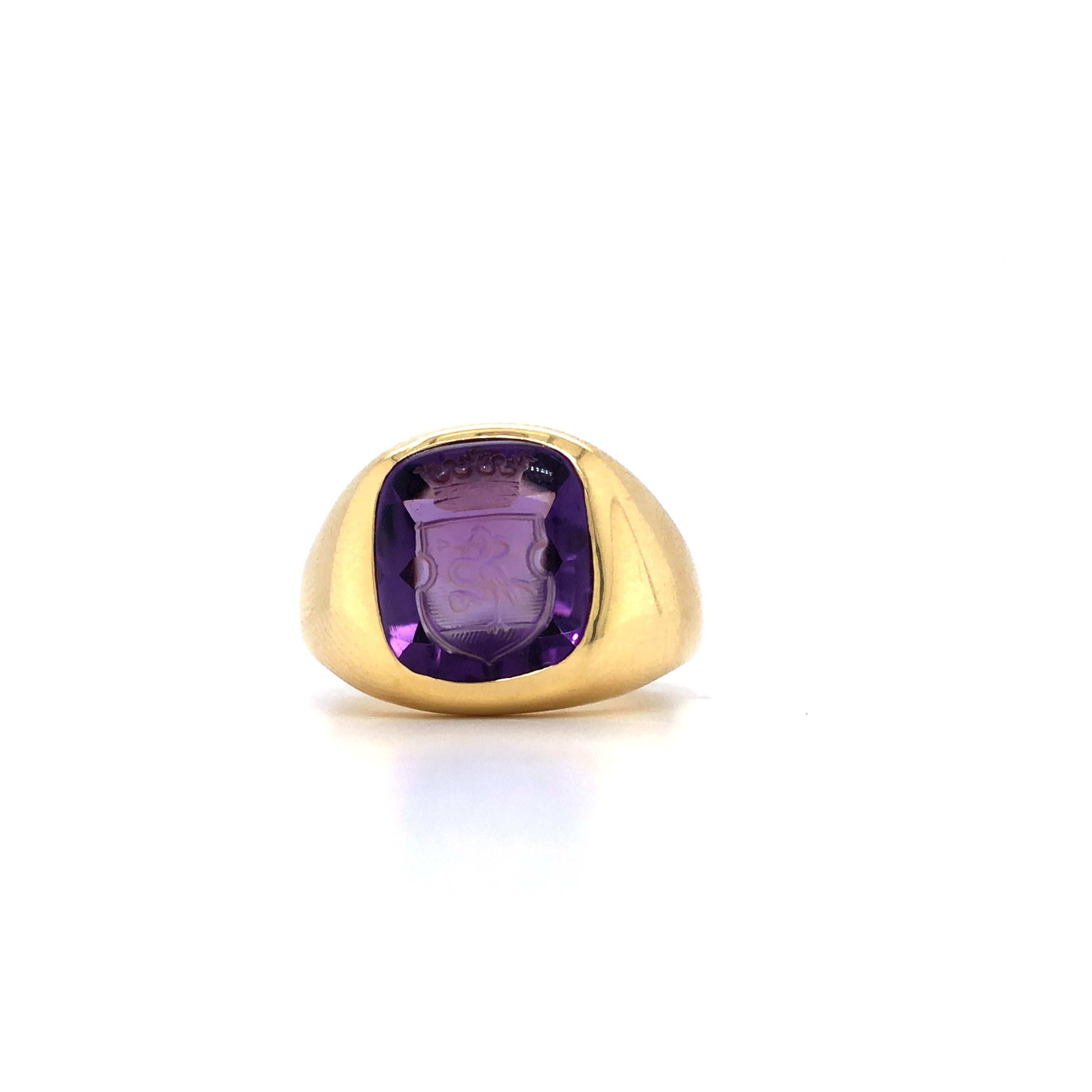 Kissenförmiger Siegelring aus Amethyst mit Tiefdruckgravur aus Gelbgold, besetzt mit einem handgeschliffenen Amethysten von 12,0 × 10,5 mm und einem eingravierten heraldischen Schild mit Vogel- und Kronenmotiv. Der Stein wird als echter