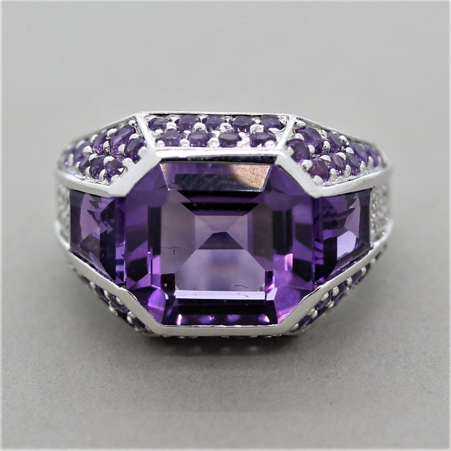 A sleek and elegant ring featuring a large square shaped amethyst. It has a bright purple color and is free of any visible inclusions allowing the brilliance of the stone to come out. It is accented by additional amethysts which are round cut and
