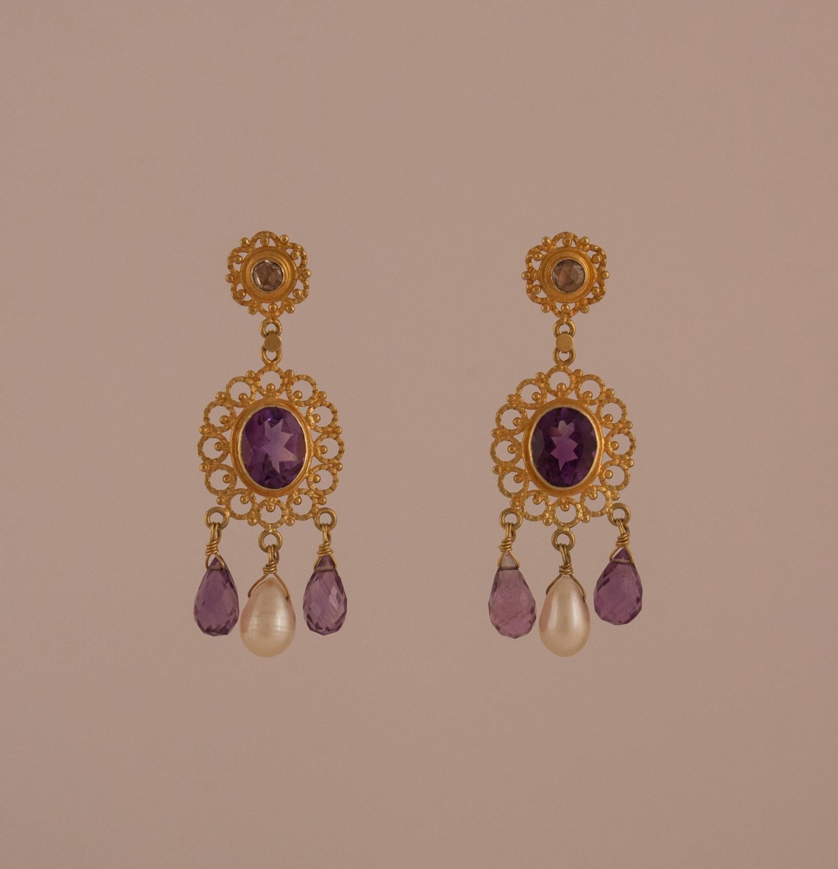 Faceted amethysts and rose cut diamonds are the centerpieces of these intricately hand tooled pair of 18 karat gold Victorian style chandelier earrings.     