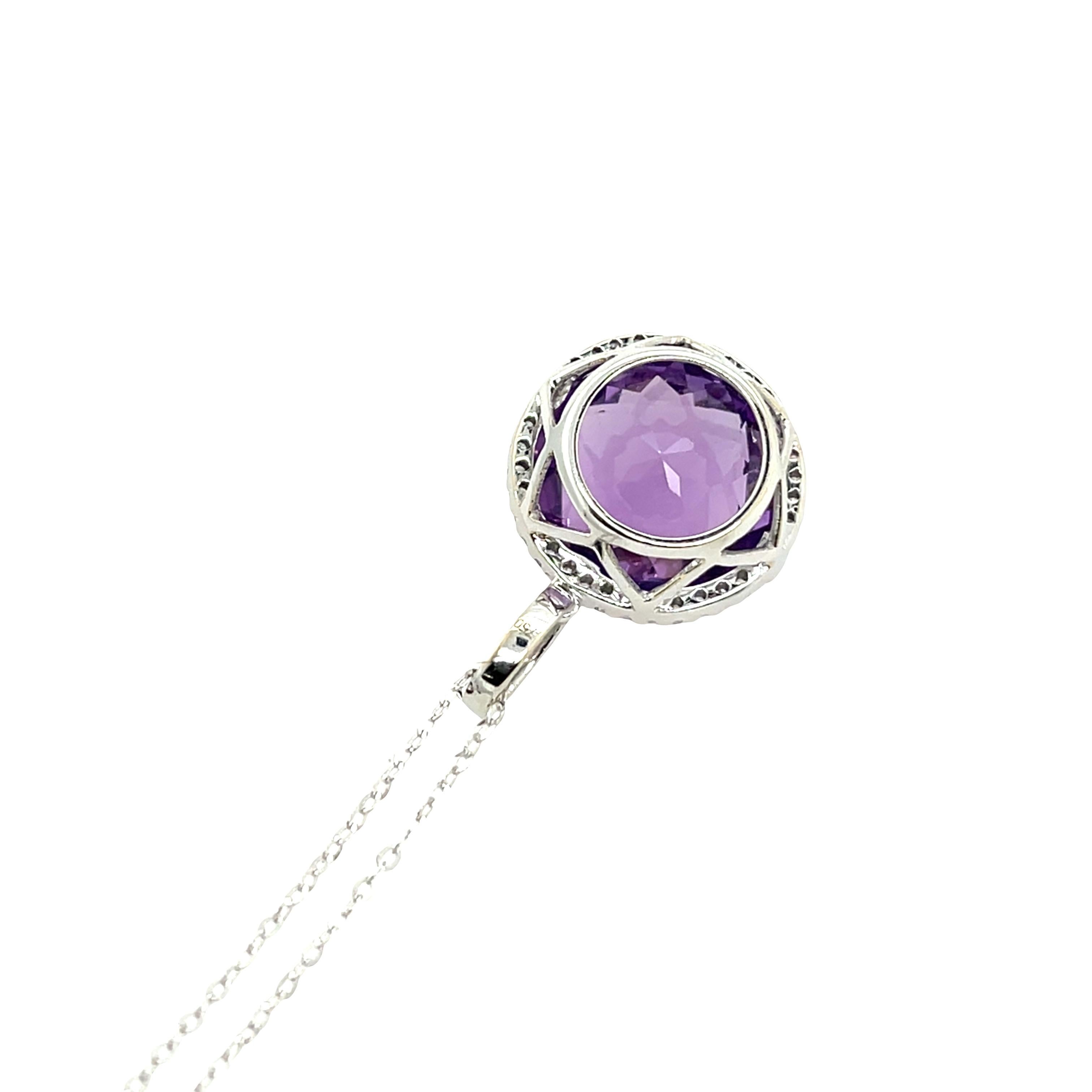 Este exquisito colgante exhibe una rica amatista de talla oval, bellamente engastada en lujoso oro blanco de 18 ct. 
Alrededor de la pieza central hay un halo de diamantes redondos naturales talla brillante, que añaden un brillo y una elegancia