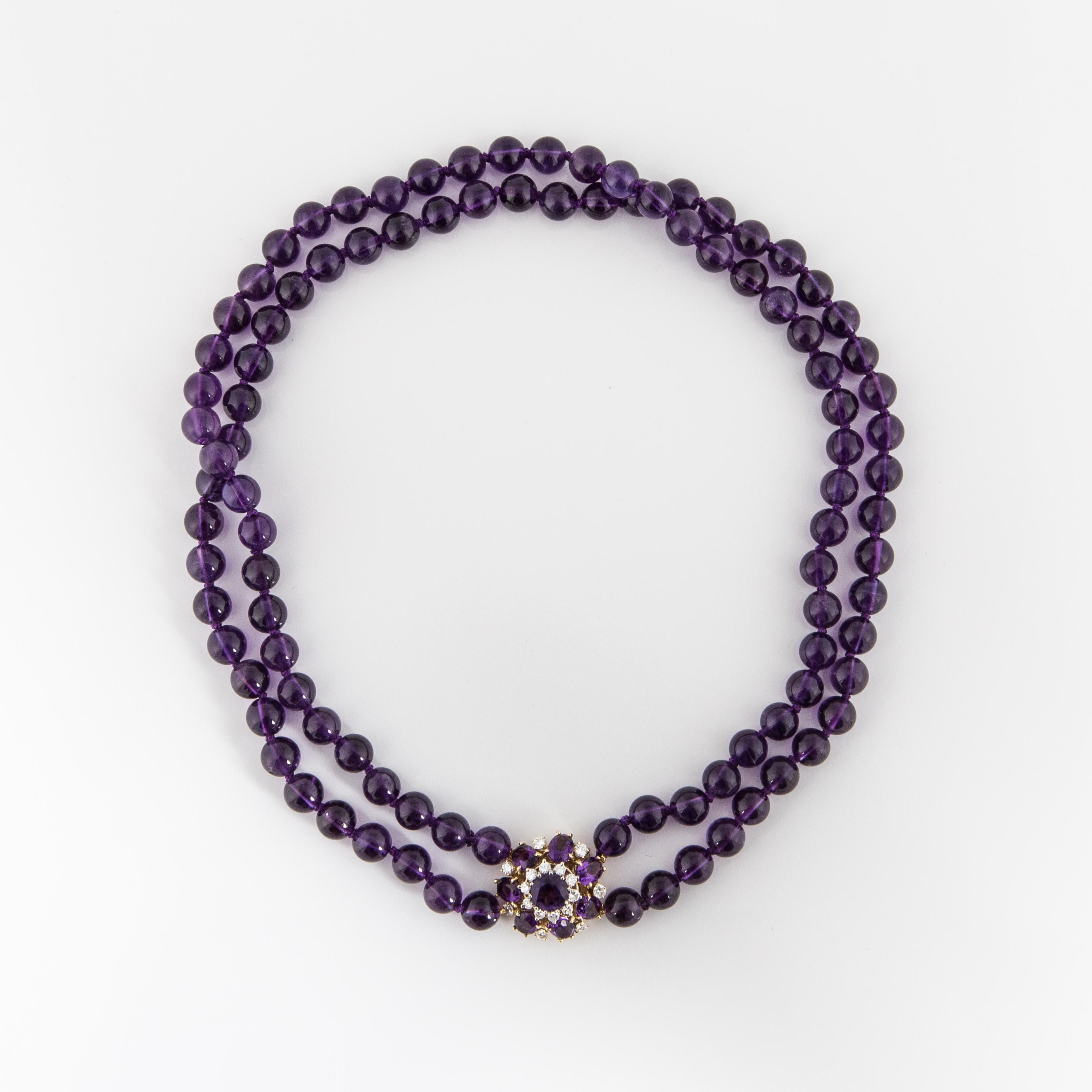 Amethyst bead double-strand necklace with 18K yellow gold diamond and amethyst clasp.  There are 100 amethyst beads measuring 8mm.  The clasp contains 7 oval amethysts that total 7 carats framing 1 round amethyst that totals 1.75 carats and 17 round