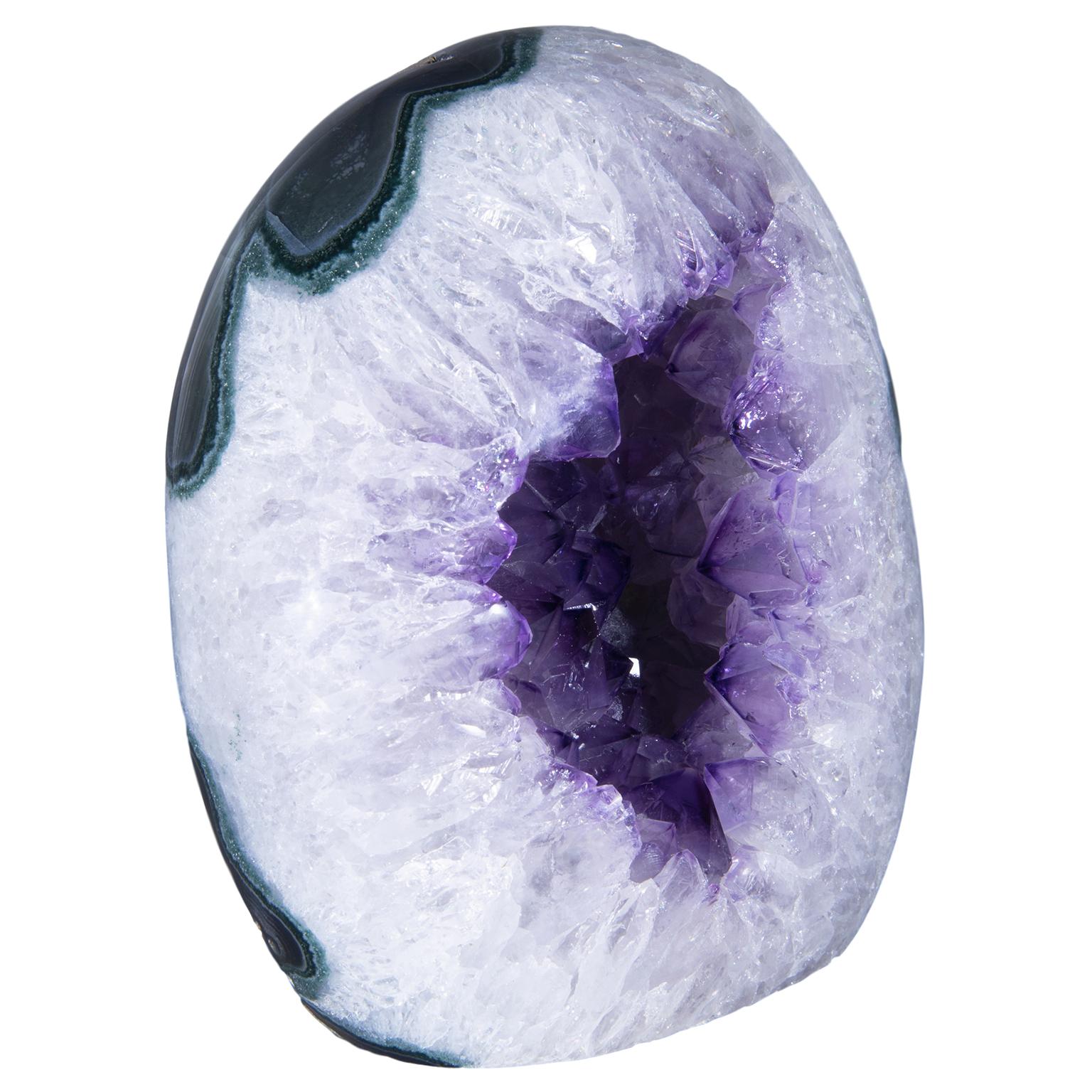 Colors fuse together in this uniquely beautiful piece, presenting the viewer with a small geode polished in the round. 

At the heart of the piece we can see intense deep purple amethyst crystals with an impressive peak size, surrounded by a white