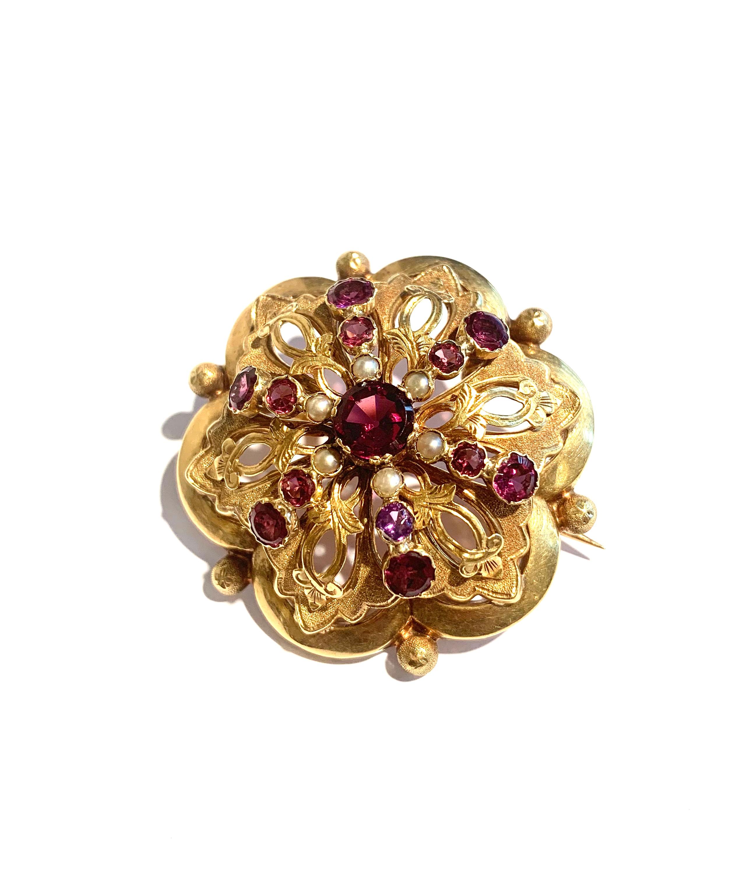 Brooch set with amethyst, garnet and pearls.

The main stone is surounded by brillant cut amethysts and garnets, orned by six grey pearls.

18 carats yellow gold, 750/00th (eagle's head hallmark punch).

Dimensions : 43 x 41 x 20 mm (1.69 x 1.61 x