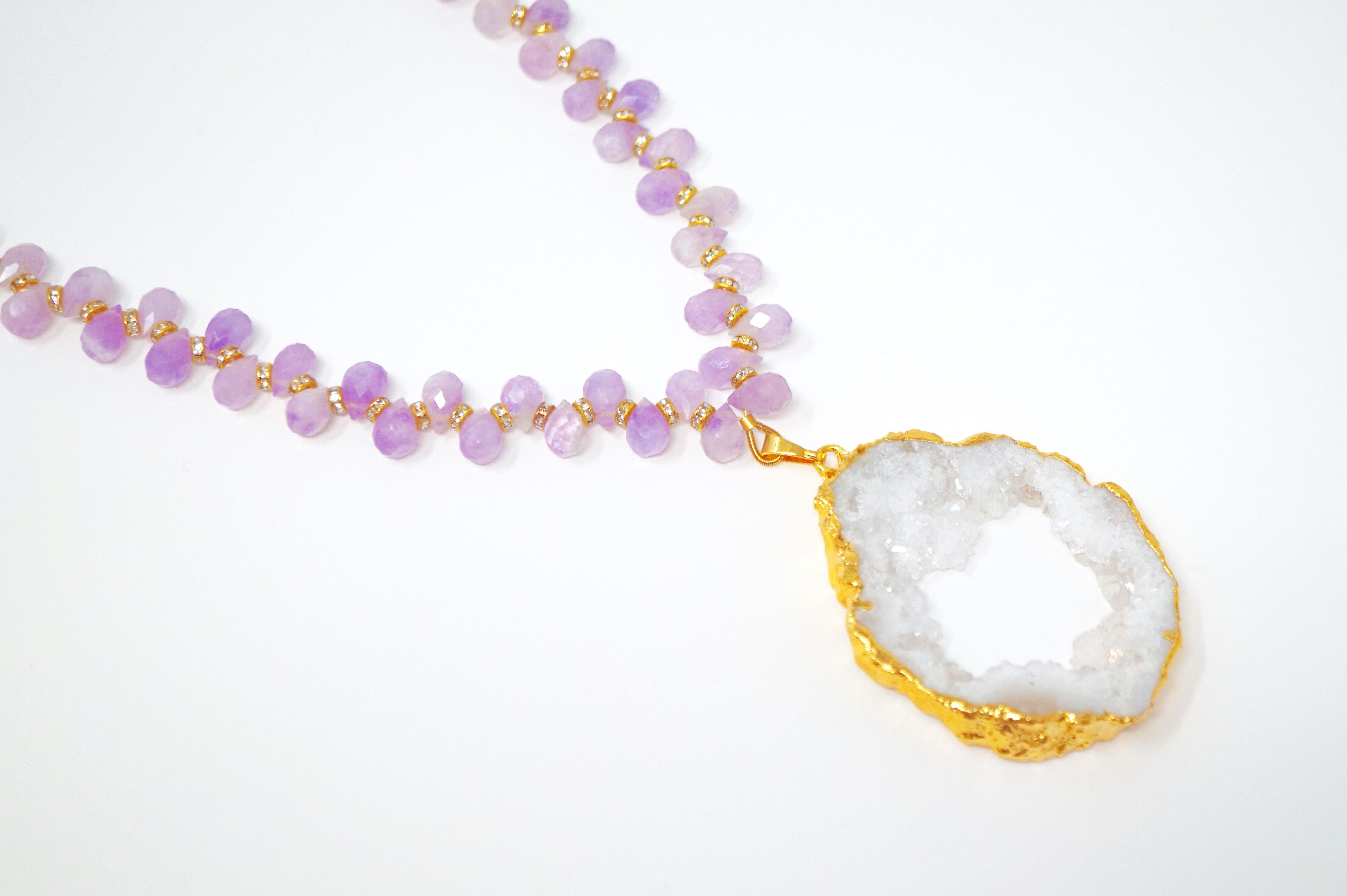 This gorgeous gemstone pendant necklace is composed of faceted teardrop Amethyst gemstones flanked by gold-plated Swarovski crystal accent beads with a natural druzy geode slice pendant with gold electroplated edges.

DETAILS:
- Clasp closure
-