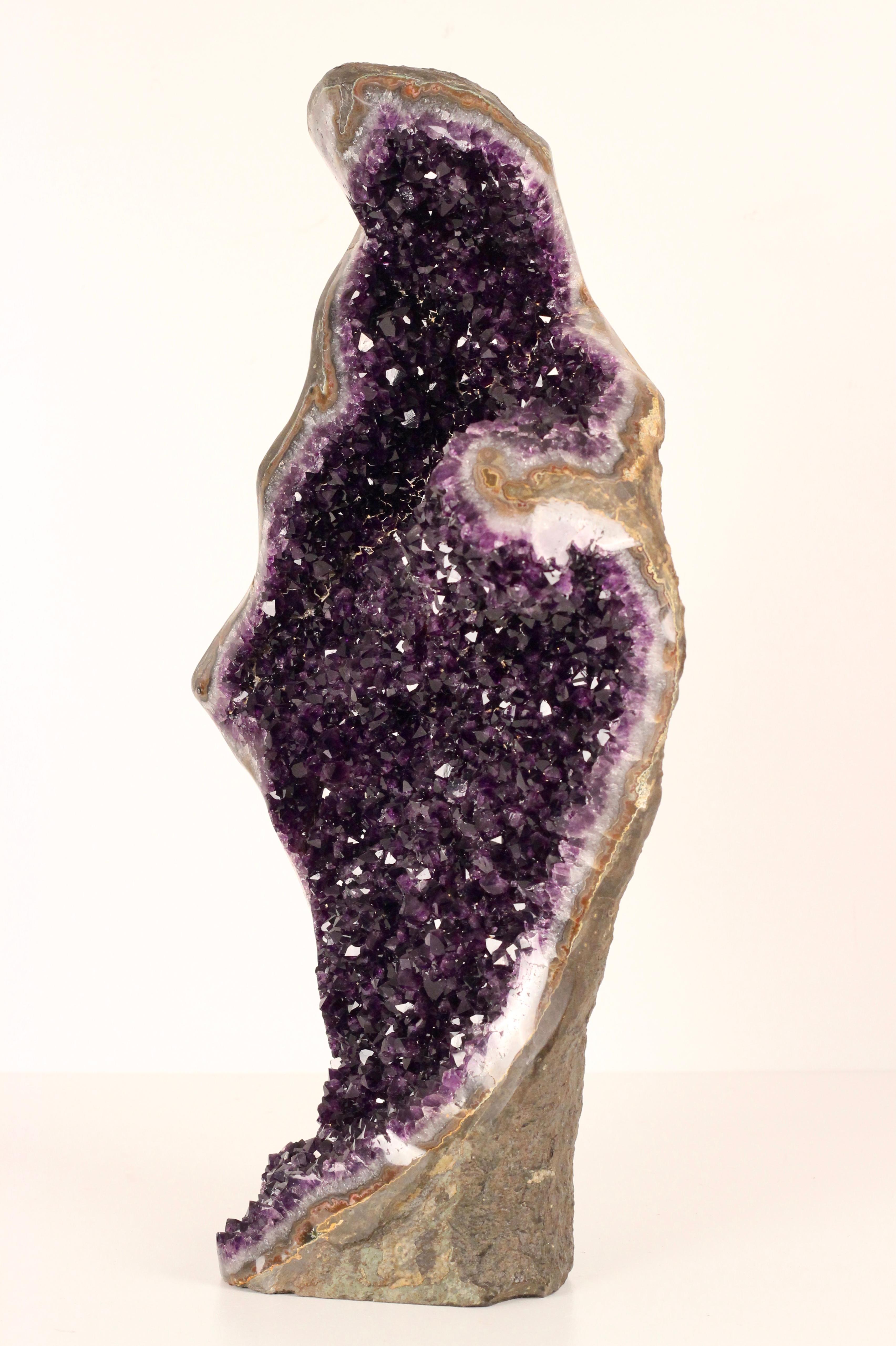This Gem grade, Amethyst Geode crystal Sculpture, resembles in shape and silhouette that of a shrouded woman holding a swaddled baby. And would work well in a Boho Chic Styled Interior. The Geode originates from Uruguay where they are mined from the
