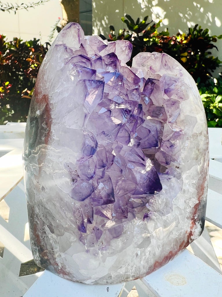 Natural amethyst and quartz crystal specimen surrounded by agate stone in hues of purple, white, dark green, and rusty orange. Taking over a million years to form, each geode is unique, adding an organic modern design element to any room. Can be