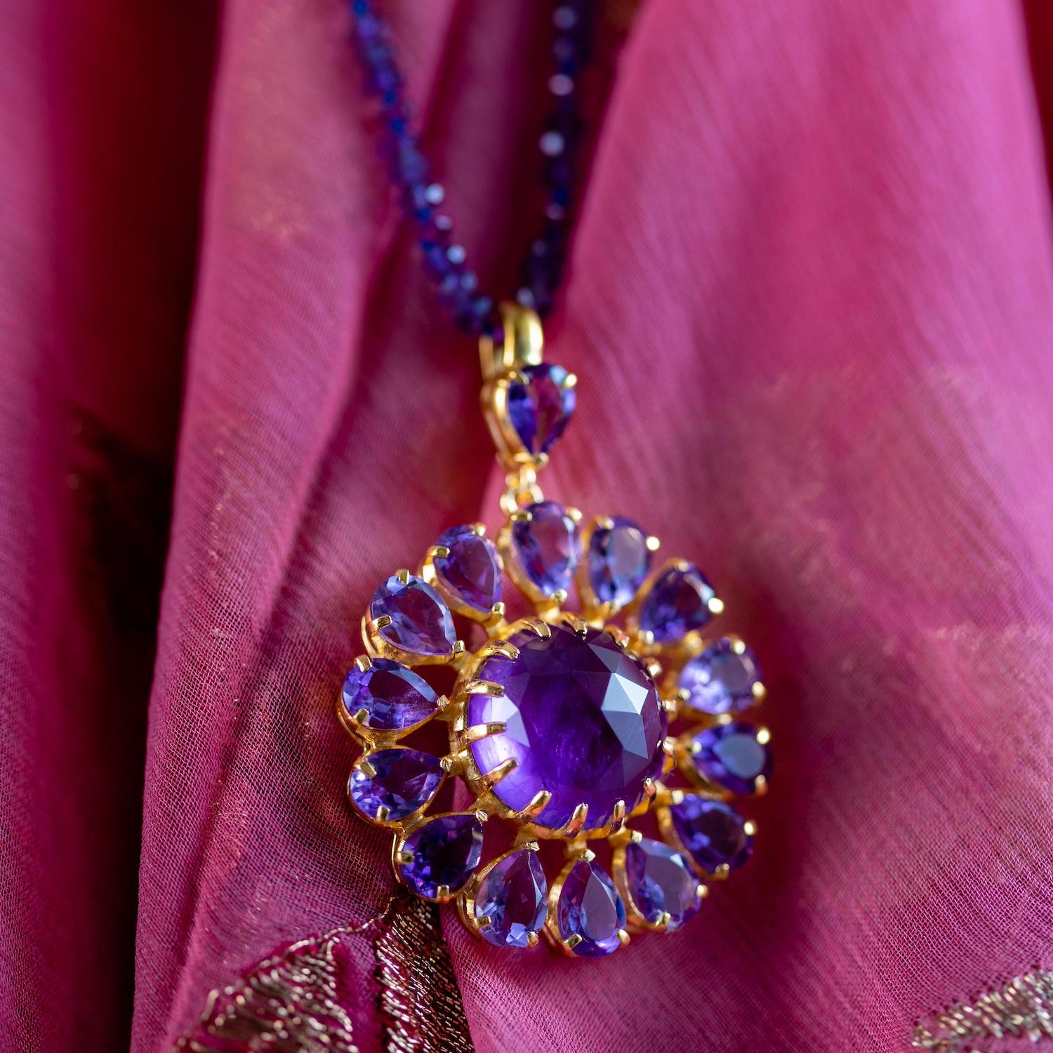 

Questo ciondolo con ametista è realizzato con ametiste a forma di pera tagliate a mano. Il ciondolo è stato lanciato alla London Fashion Week ed è in edizione limitata. È realizzato in argento sterling con placcatura in oro micron e ha una catena