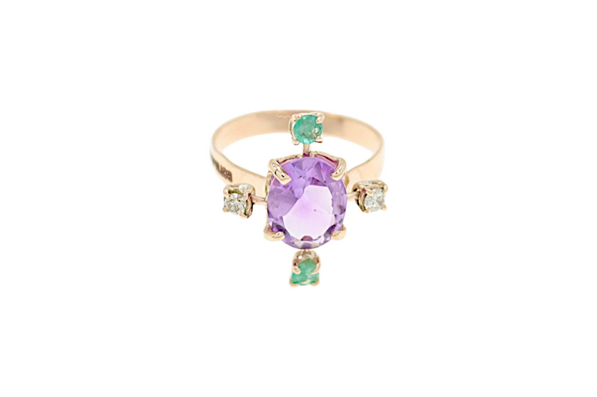 The ring features a central amethyst surrounded by two diamonds and two emeralds, forming a four-pointed star. The oval brilliant-cut amethyst measures 8x10 mm and weighs 2.10 ct. The two natural white brilliant-cut diamonds have a total weight of