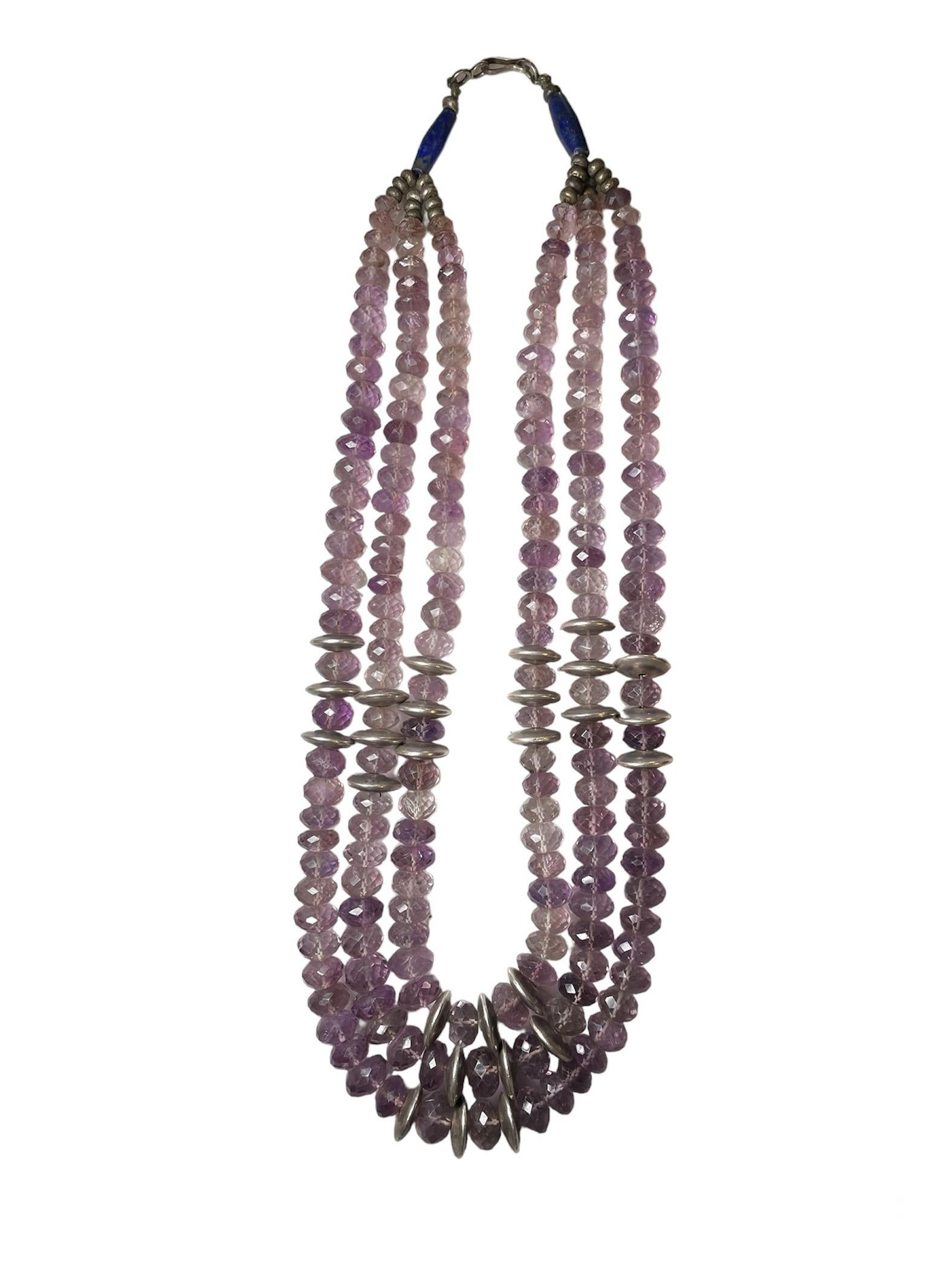 Questa è una collana a più fili di ametista, lapislazzuli e argento. Raffigura una collana a tre file di ametiste sfaccettate a forma di dodecaedro ovale, impreziosita da una serie di tre pezzi d'argento a forma di disco volante al centro e ai lati