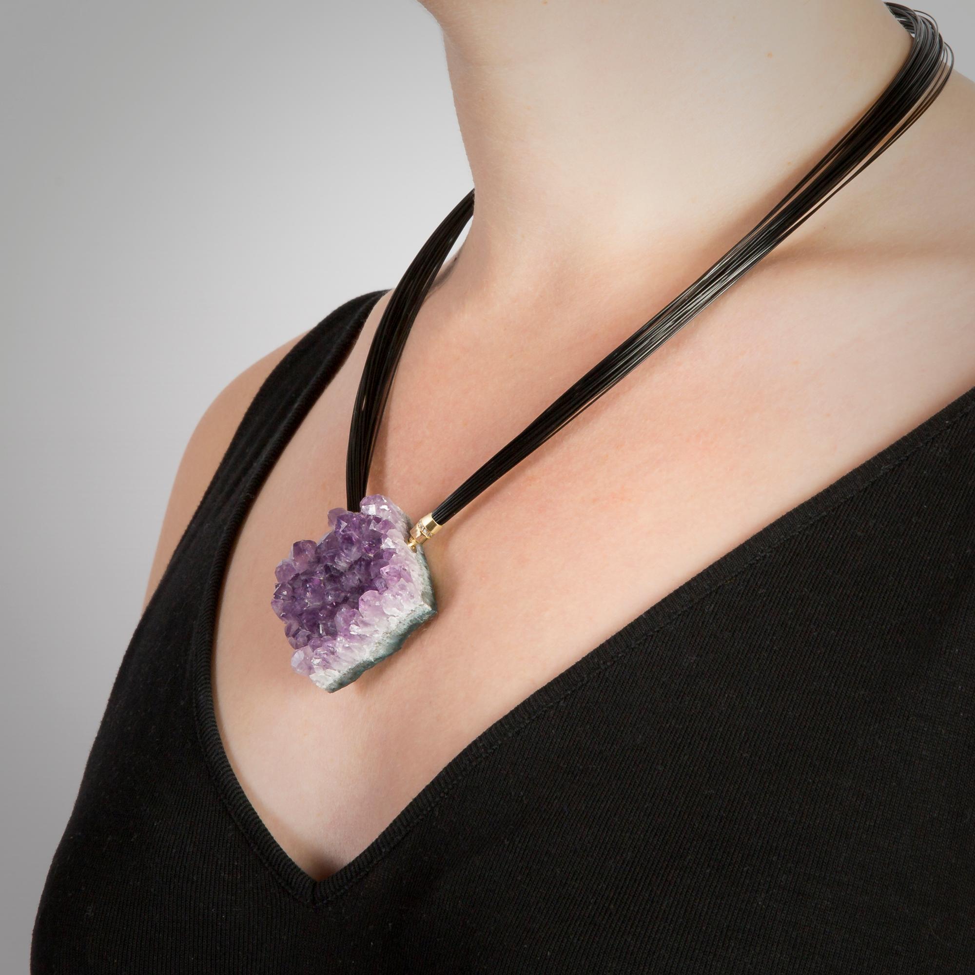 This unique Amethyst necklace is made of a single impressive piece of Amethyst geode which is fixed onto a multi strand black cable by two diamond set 18 Karat Gold bayonet clasps. 

Made by hand in our family run Northern Irish jewellery workshop.
