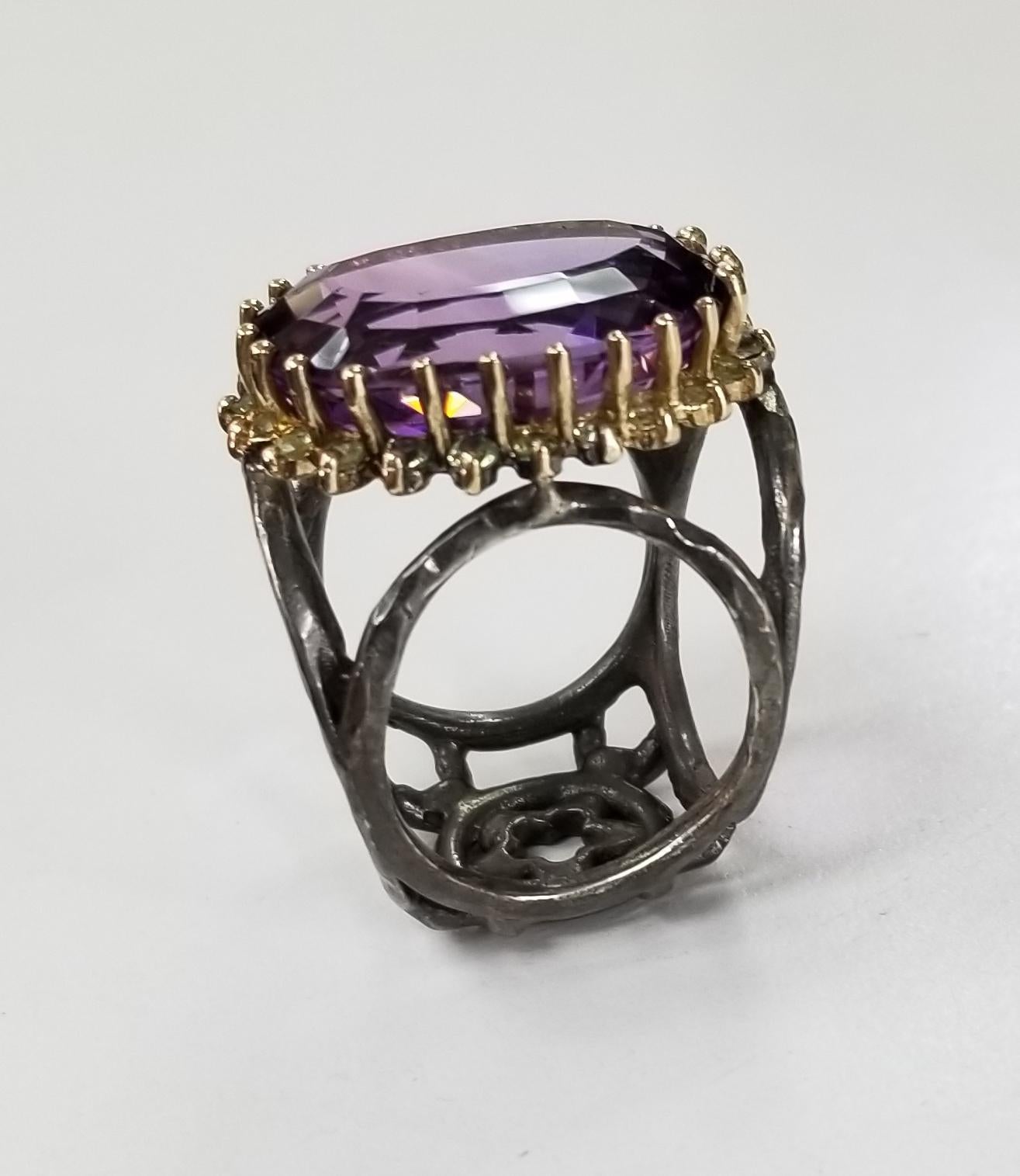 Amethyst oval 21.87cts. with peridot 14 karat yellow gold and silver, containing 22 round peridot weighing .55pts. and 1 large oval amethyst weighing 21.87cts.  The ring is made to fit 2 different fingers size 6 and 8.