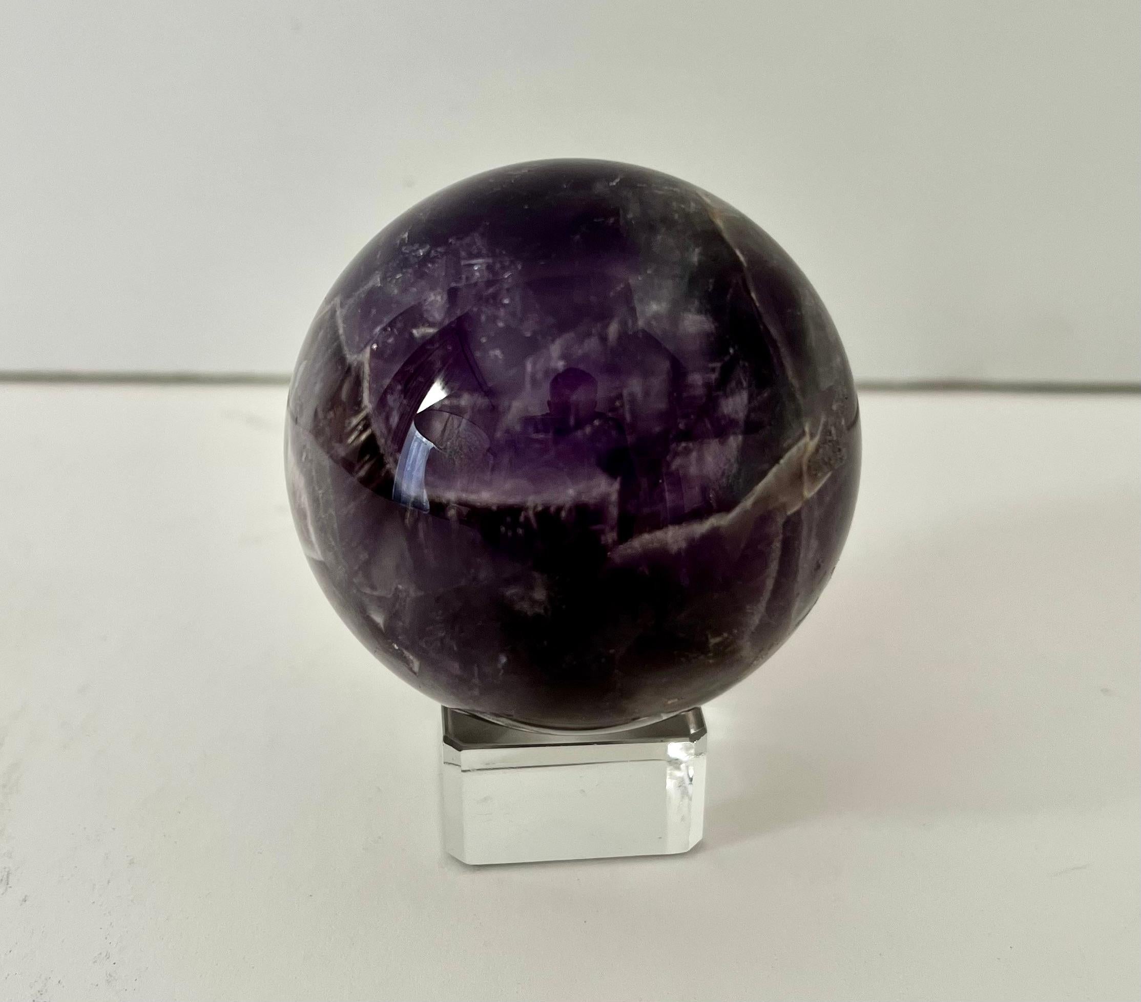 A small paperweight on a square crystal stand with a divot to hold the sphere. A compliment to any desk or work station or on a cocktail table. A beautiful piece.