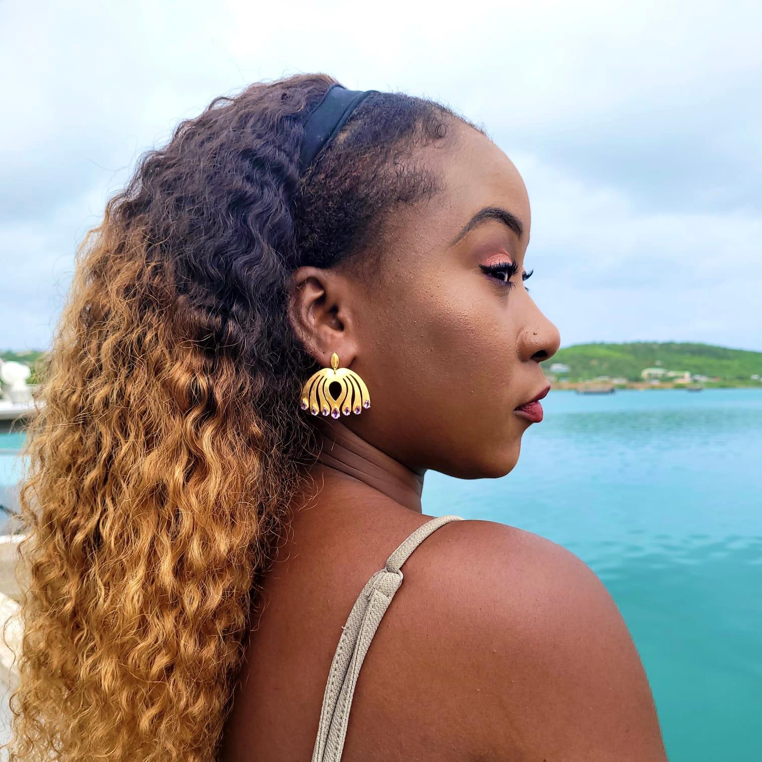 Open halo raindrops on the center of these ethereal earrings draw inspiration from the eyes of a peacock feather, symbolic of strength and wisdom. Amethyst stones prong set on the bottom front of each glorious feather gives them a touch of purple