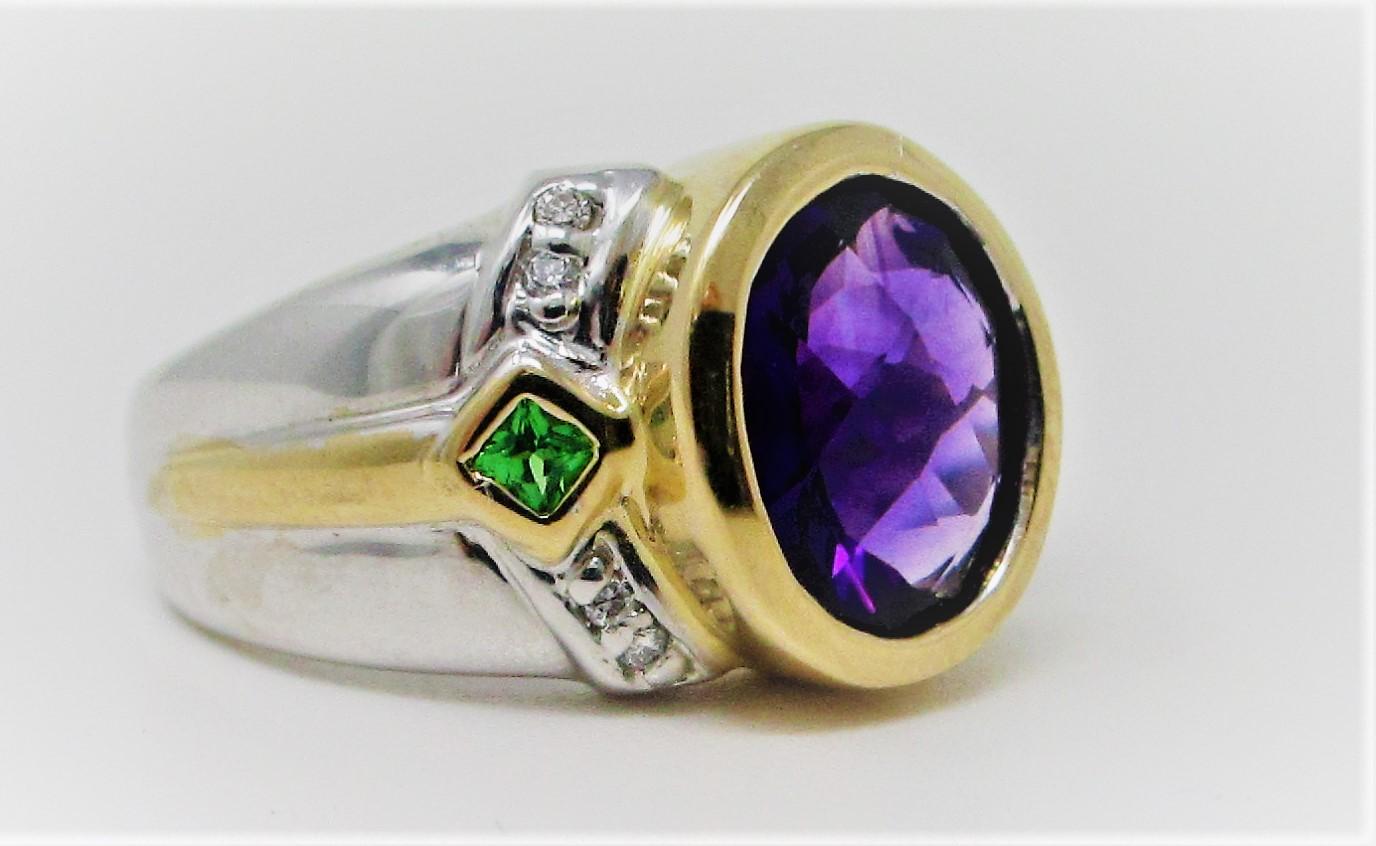 Set in two tone 14 Karat yellow gold, this lovely amethyst is bezel set and accented with peridot and diamonds.  Size 7 3/4.
