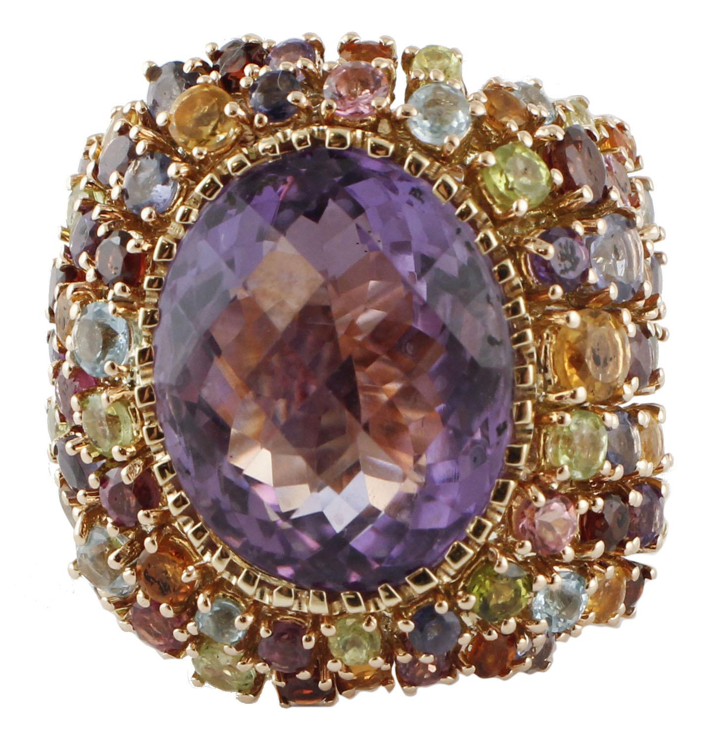 Precioso anillo de cóctel realizado en estructura de oro rosa de 14k. El anillo está montado con una gran amatista central de color intenso, rodeada por muchas piedras de distintos colores: peridotos, amatistas, topacios, turmalina, aguamarina y