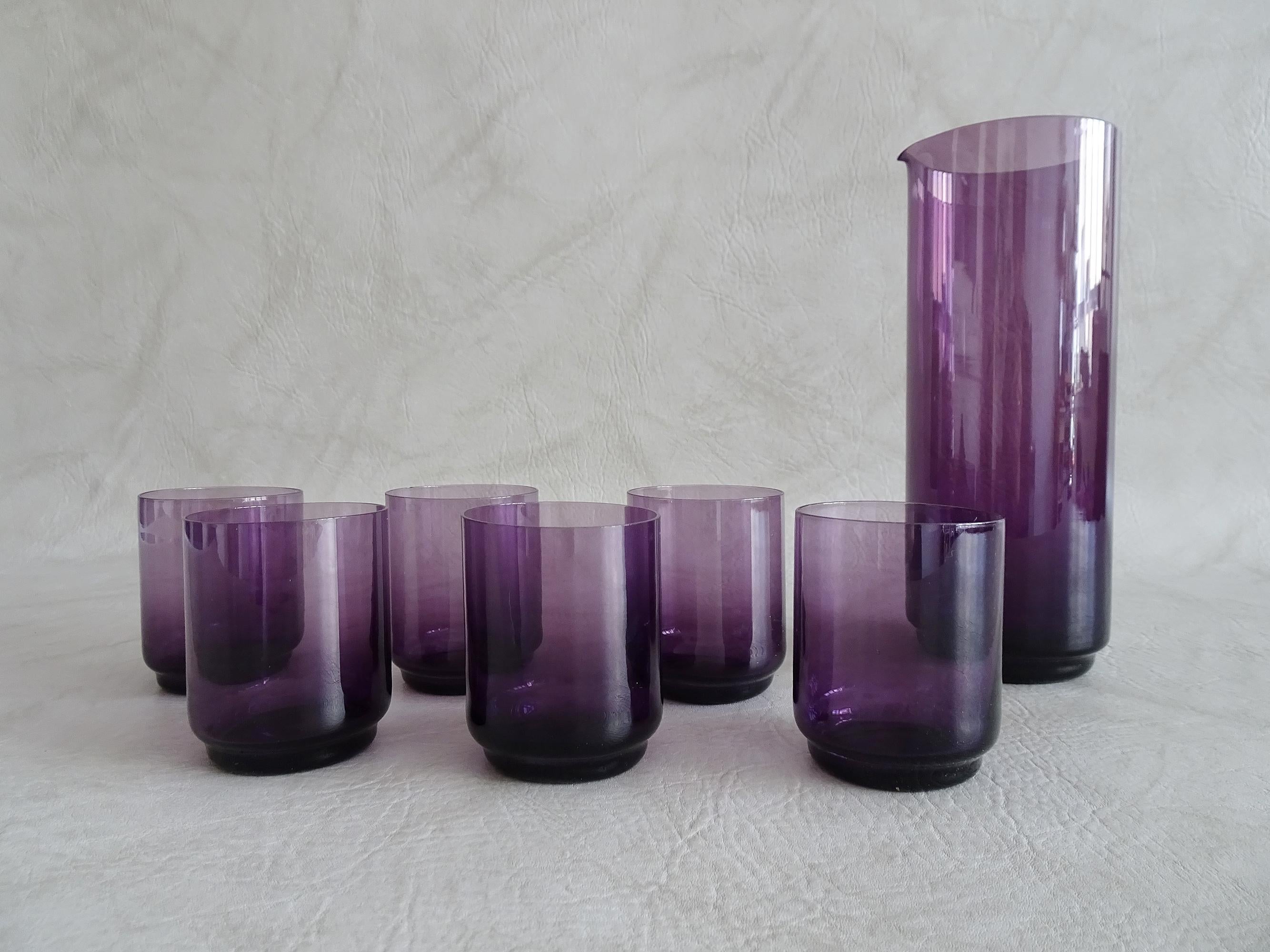 Seven-piece glasses set, consisting of a carafe and six glasses. Clear and elegant, thin glass, hand-blown in purple from the mid-century. The minimalist design convinces immediately and is a great companion for daily needs and a decorative