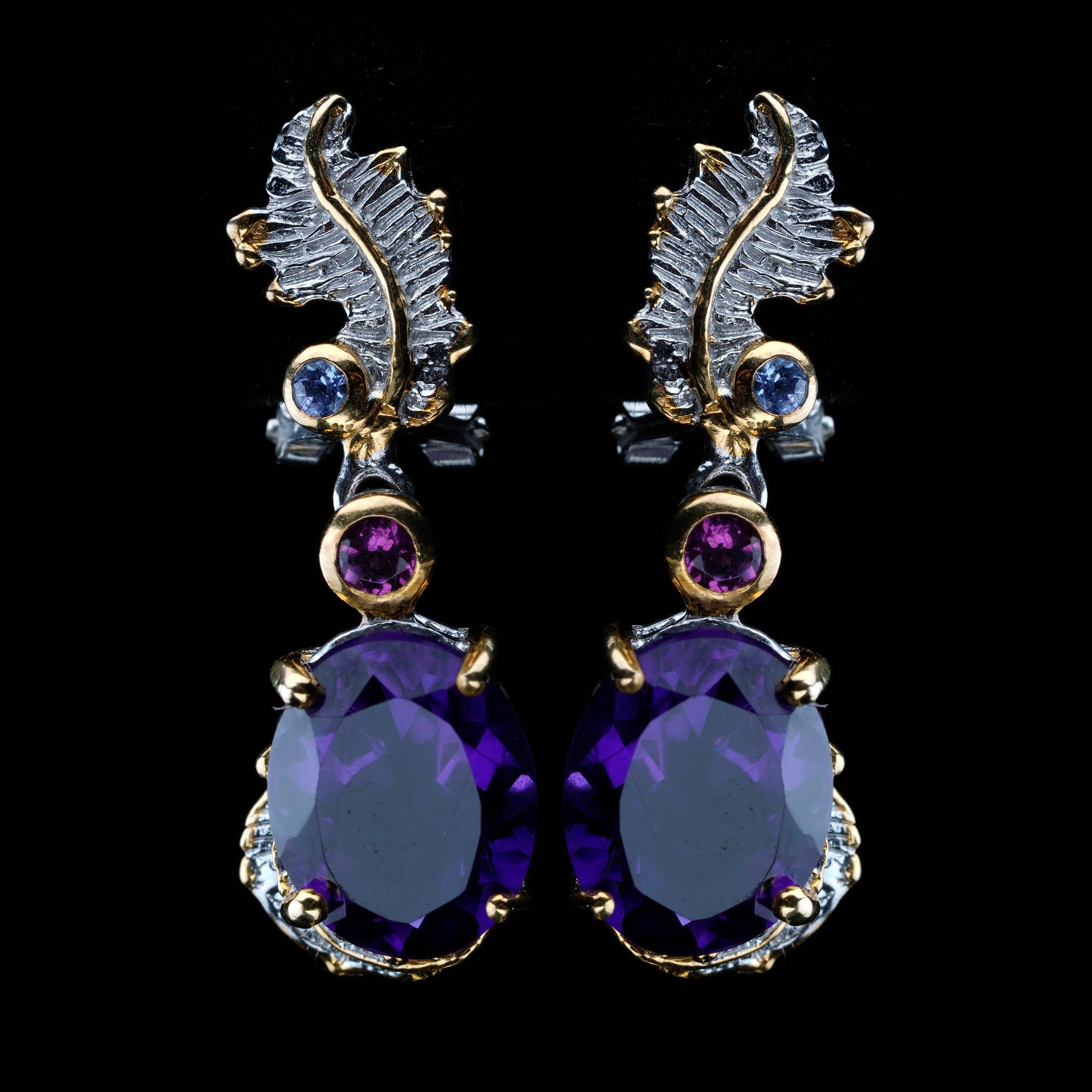Ces remarquables boucles d'oreilles (16 mm de hauteur) présentent des améthystes de taille ovale dans une monture artisanale en argent sterling oxydé et en or 14 carats. Au-dessus de chaque améthyste, une délicate cascade de grenats rhodolites et de