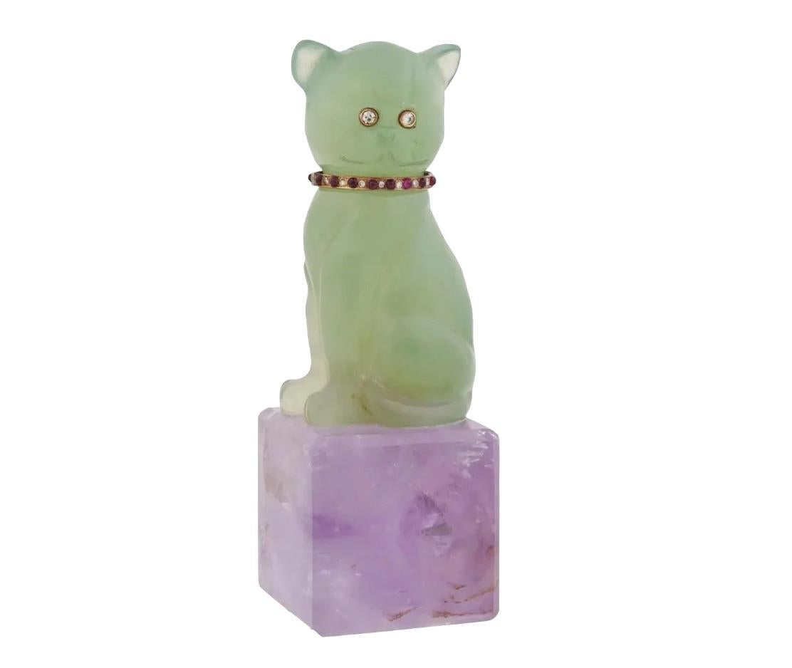 A vintage carved jade cat figurine. The figure has diamond eyes and a ruby and diamond collar in gold settings. The item is mounted on a square carved amethyst base. Collectble Jewelry And Decor For Interior Design.

Dimensions: H 4 1/4 in. All