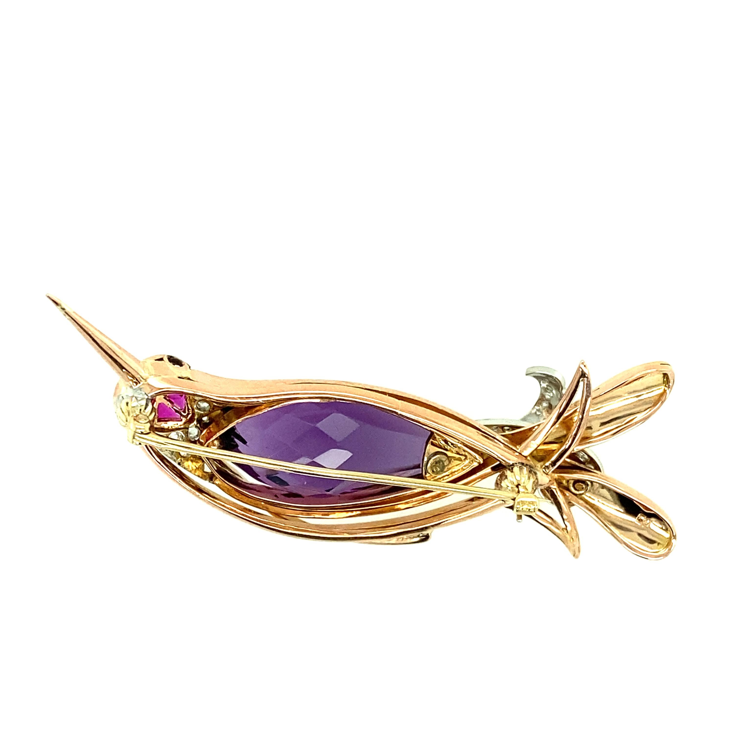 One 14 karat rose gold estate hummingbird pin set with one 1 inch x 11mm amethyst, ten pink sapphires, and twenty-four rose cut diamonds, 0.65 carat total weight with matching I/J color and SI1 clarity.  The pin measures 2.5 inches long and is