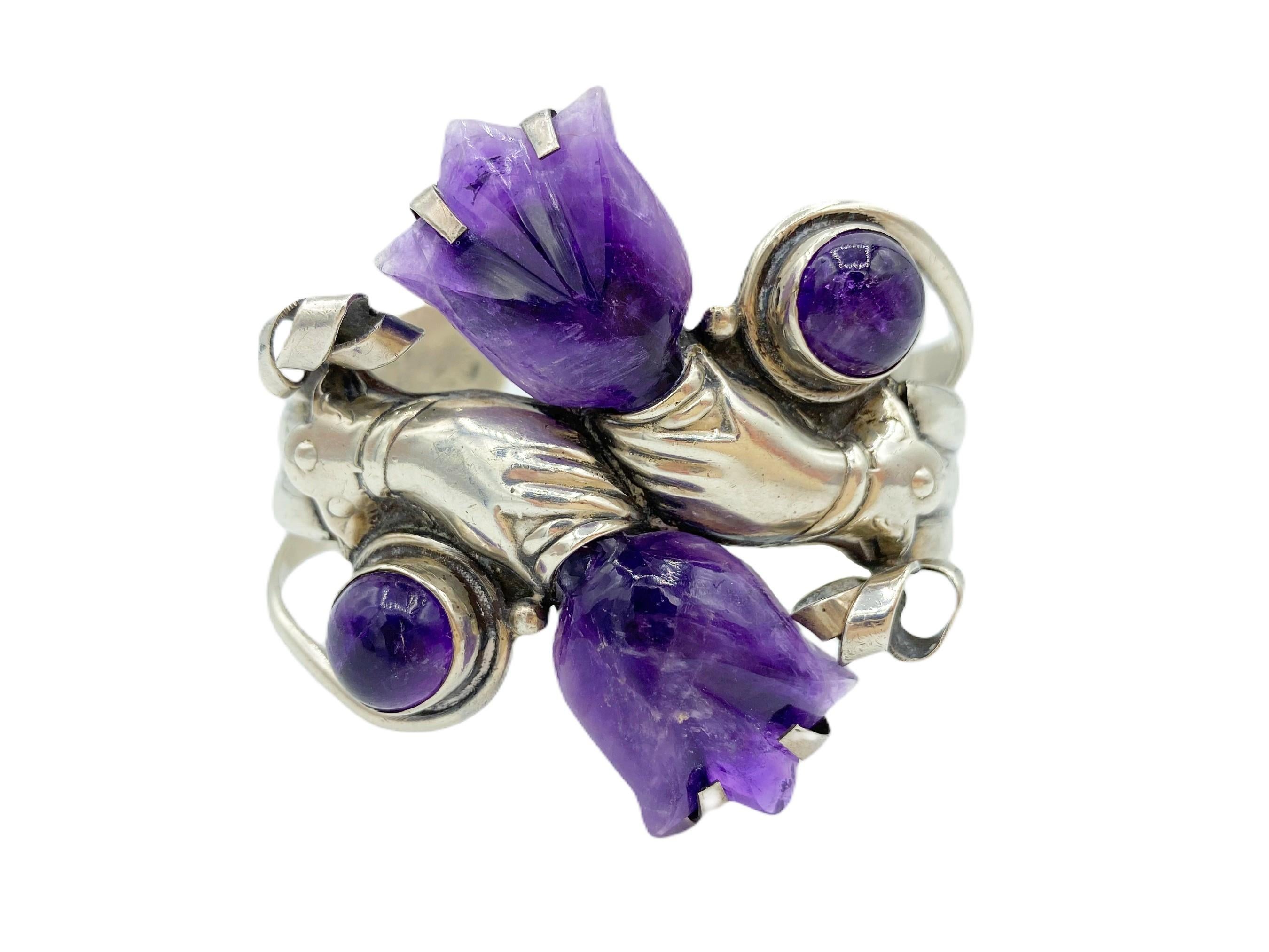 Remarkably crafted, this stunning vintage amethyst and sterling silver cuff bracelet is sure to leave a lasting impression. Inspired by an iconic William Spratling design of hands holding tulips, the bracelet features  amethysts carved into tulips,