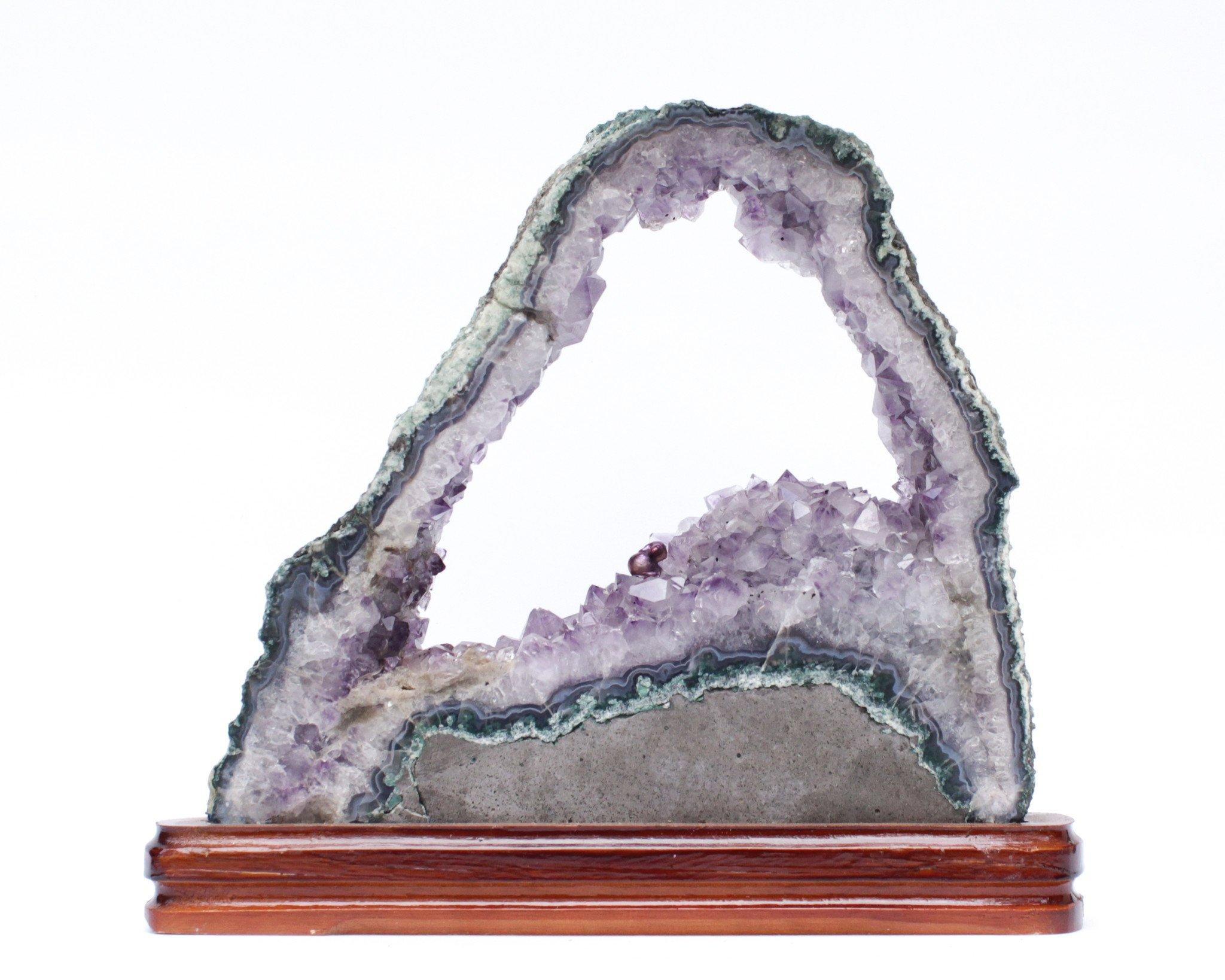 Amethyst slice with a baroque natural forming pearl on a polished wood base.

This amethyst is rare in how large it is, its beautiful shape, and its large opening in the center. The piece originally comes from Brazil. It is adorned with a baroque