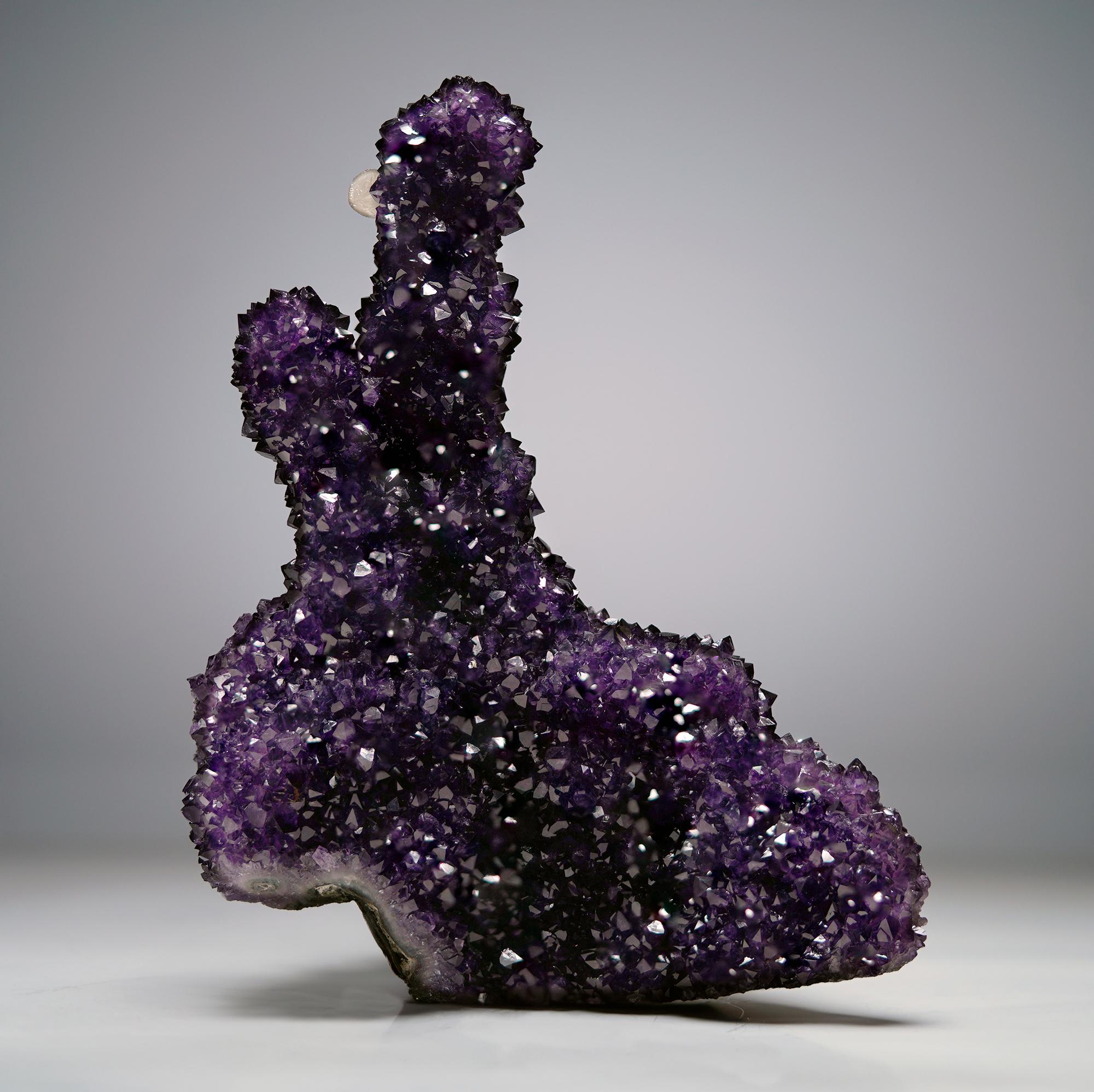Sculpture naturelle extraordinaire, cette formation uruguayenne de stalactites à double améthyste éblouit par ses cristaux d'un violet vif et profond et par un cristal de calcite blanc parfaitement positionné et nettement défini émergeant de