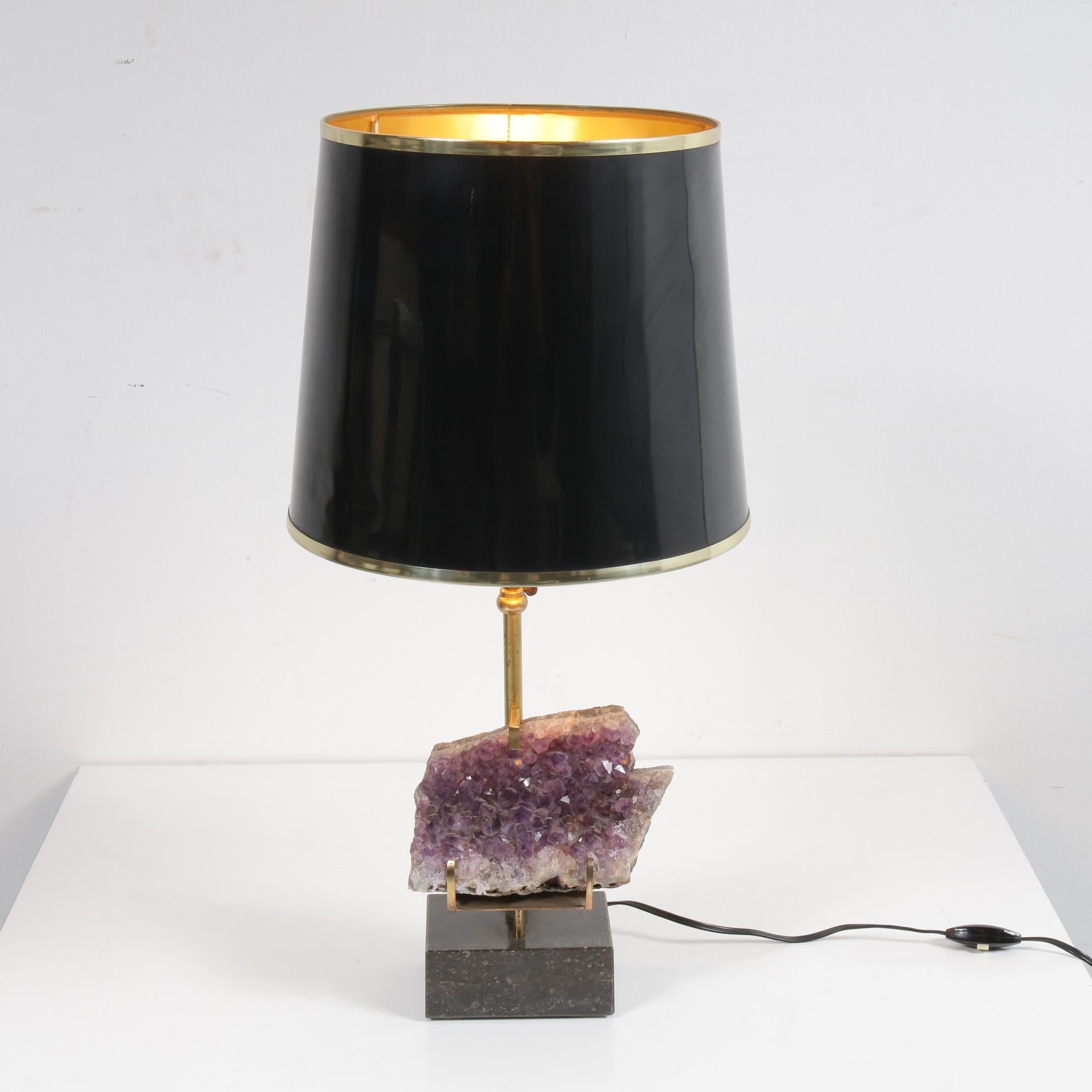 A rare table lamp with beautiful Amethyst core, in the style of Willy Daro, manufactured in Belgium around 1970.

The lamp has a beautiful brass base on a Belgian black marble foot. The hood is black lacquered with brass edges. The true eyecatcher