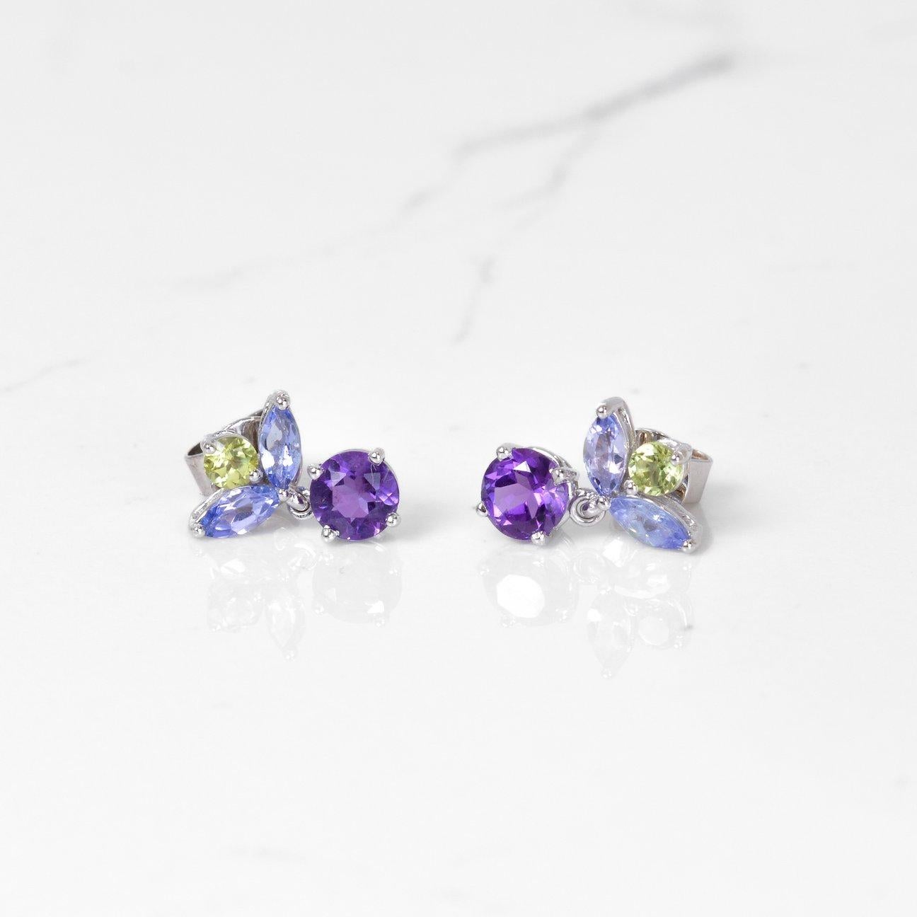 Pretty in purple! These beautiful earrings consist of gorgeous amethyst, tanzanite, and peridot gemstones, all set in 14k white gold. These earrings measure 12.6mm in length