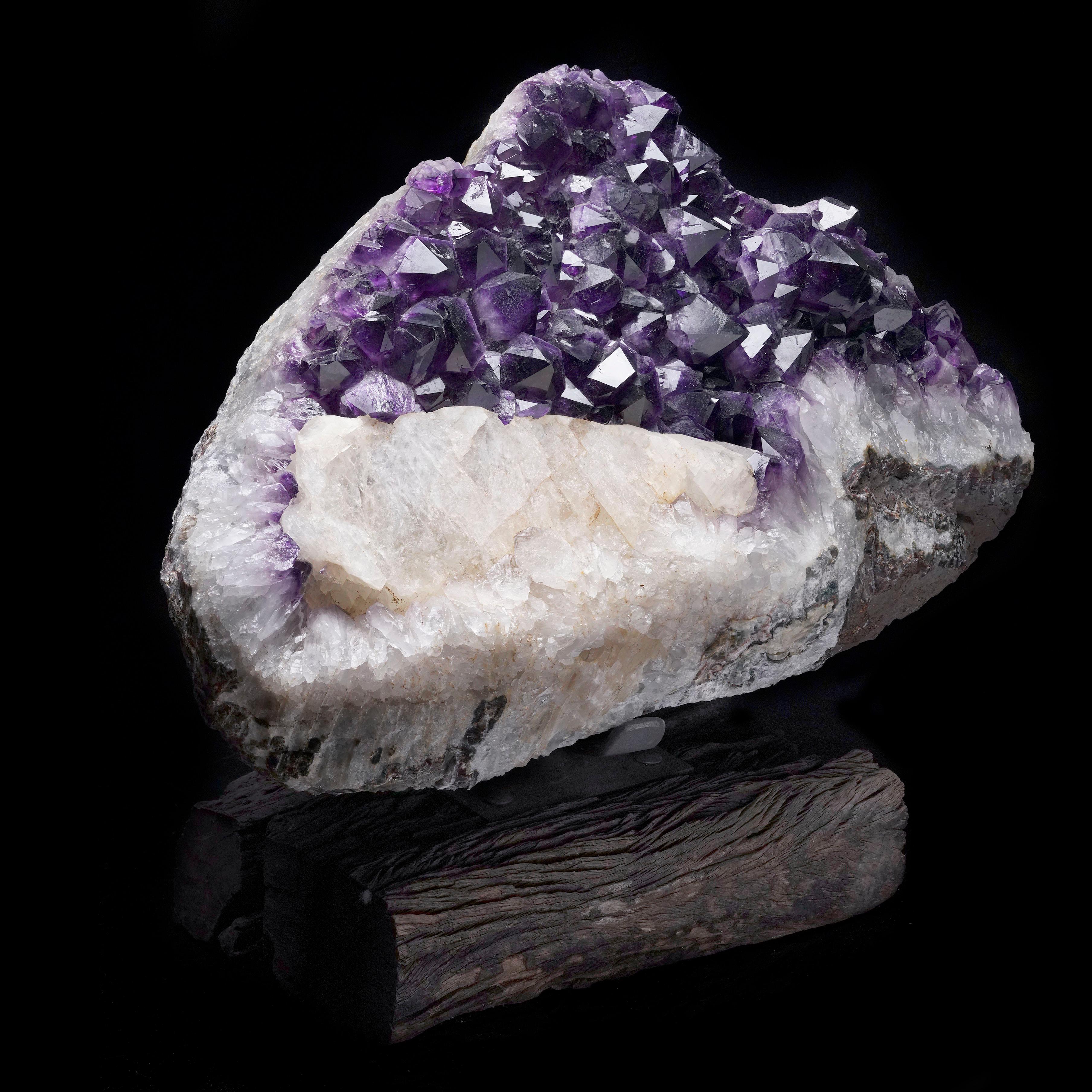 Mounted on a custom wood and metal stand for perfect display, this large, gemmy, grape jelly purple Amethyst Geode combination specimen is accented by a generous co-occurrence of Calcite. The vibrant, high-luster Amethyst points shimmer with clarity