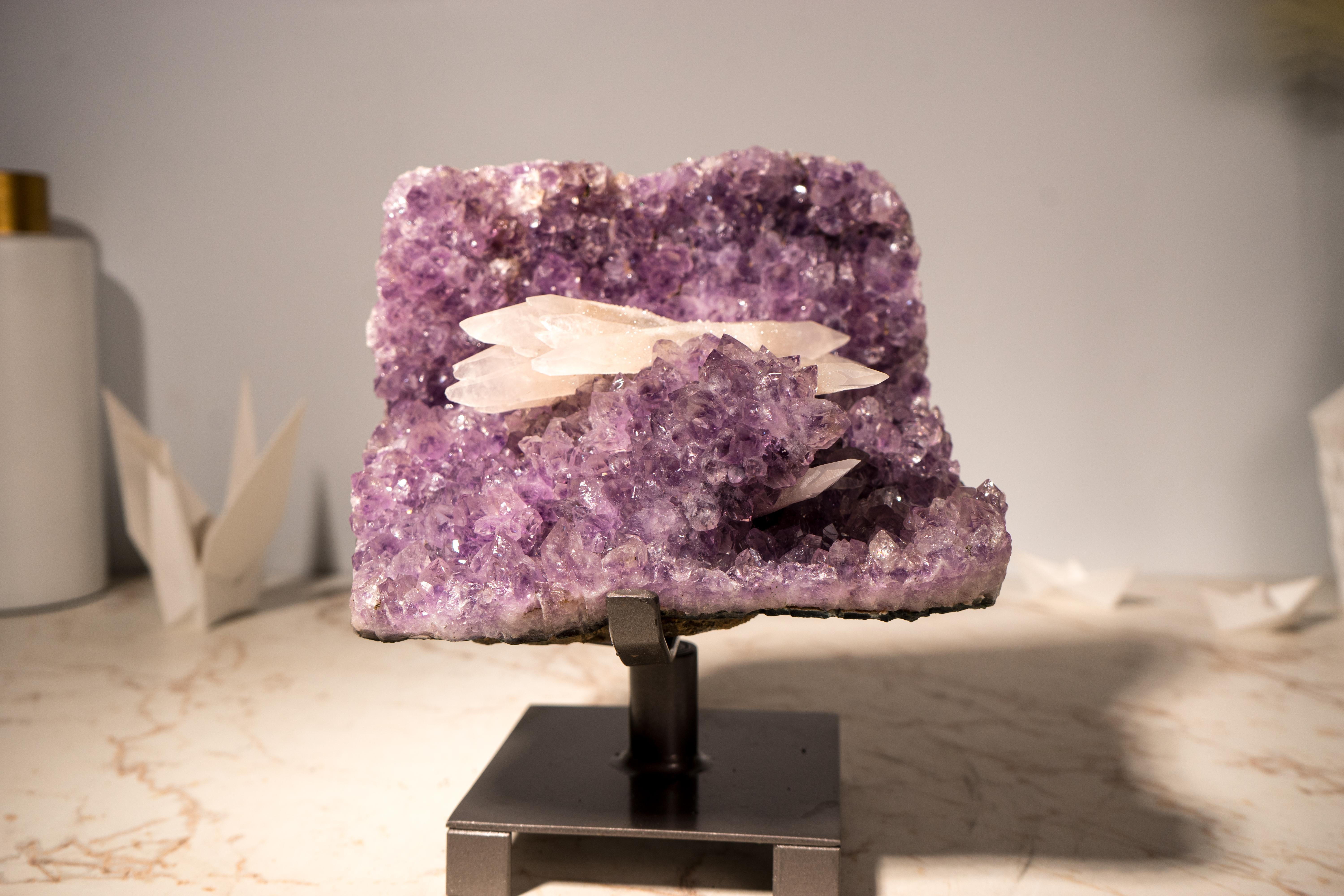 Un piccolo ma splendido gruppo di ametiste, questo esemplare di colore viola intenso mostra una rara formazione di calcite reattiva ai raggi UV disposta a spade incrociate, con calcite intatta a doppia terminazione che cresce tra ametiste color