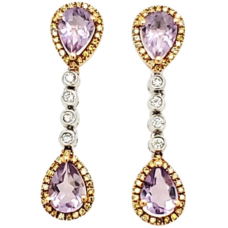 Amethyst, Yellow Diamond, and White Diamond Gold Earrings:

A scintillating pair of earrings composed of fine quality natural pear shaped Amethysts weighing a total of 2.22 carat, each one surrounded by a halo of Yellow Diamonds that weigh a total